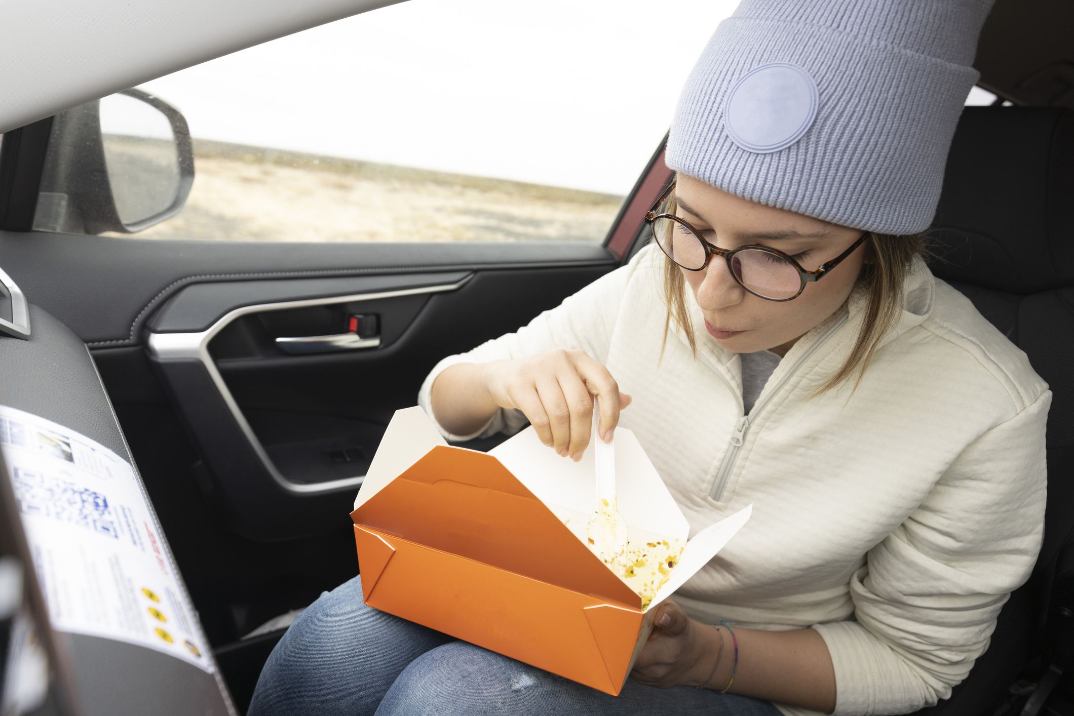 Female tourist eats pasta while sitting in a car