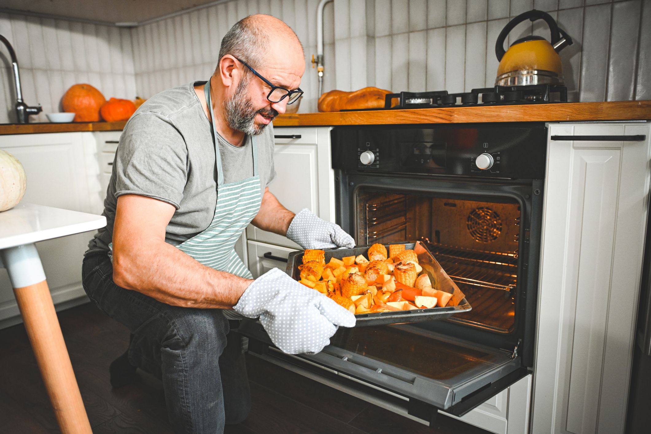 man preparing a festive dinner, baking vegetables in the oven