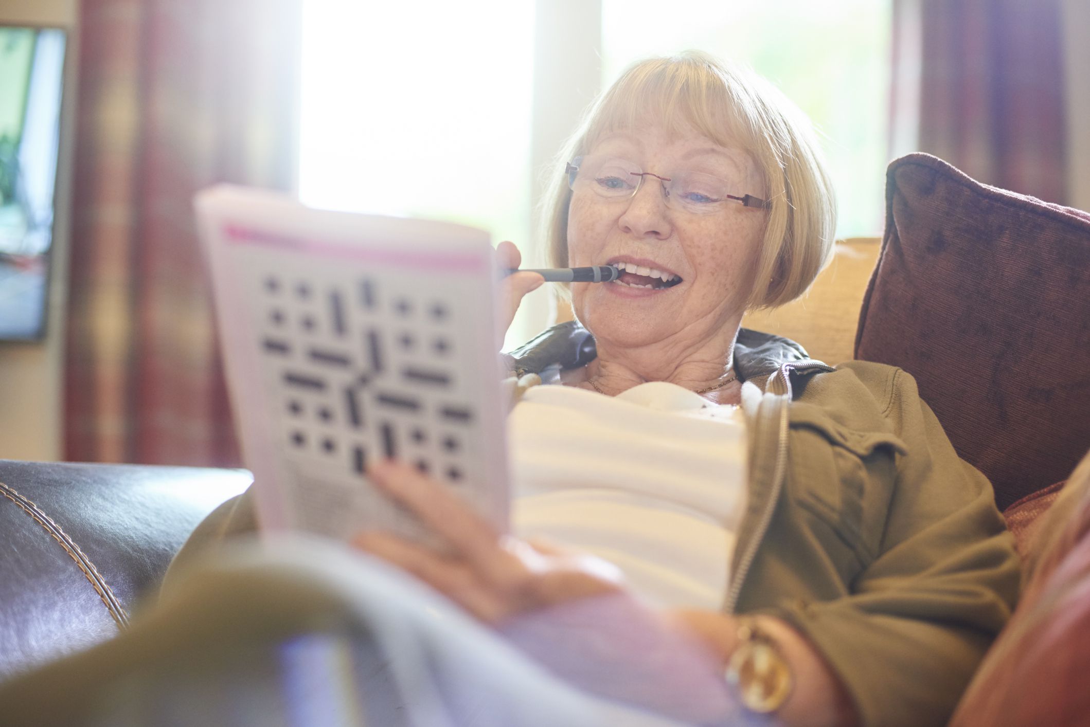 senior woman doing crossword puzzle at home