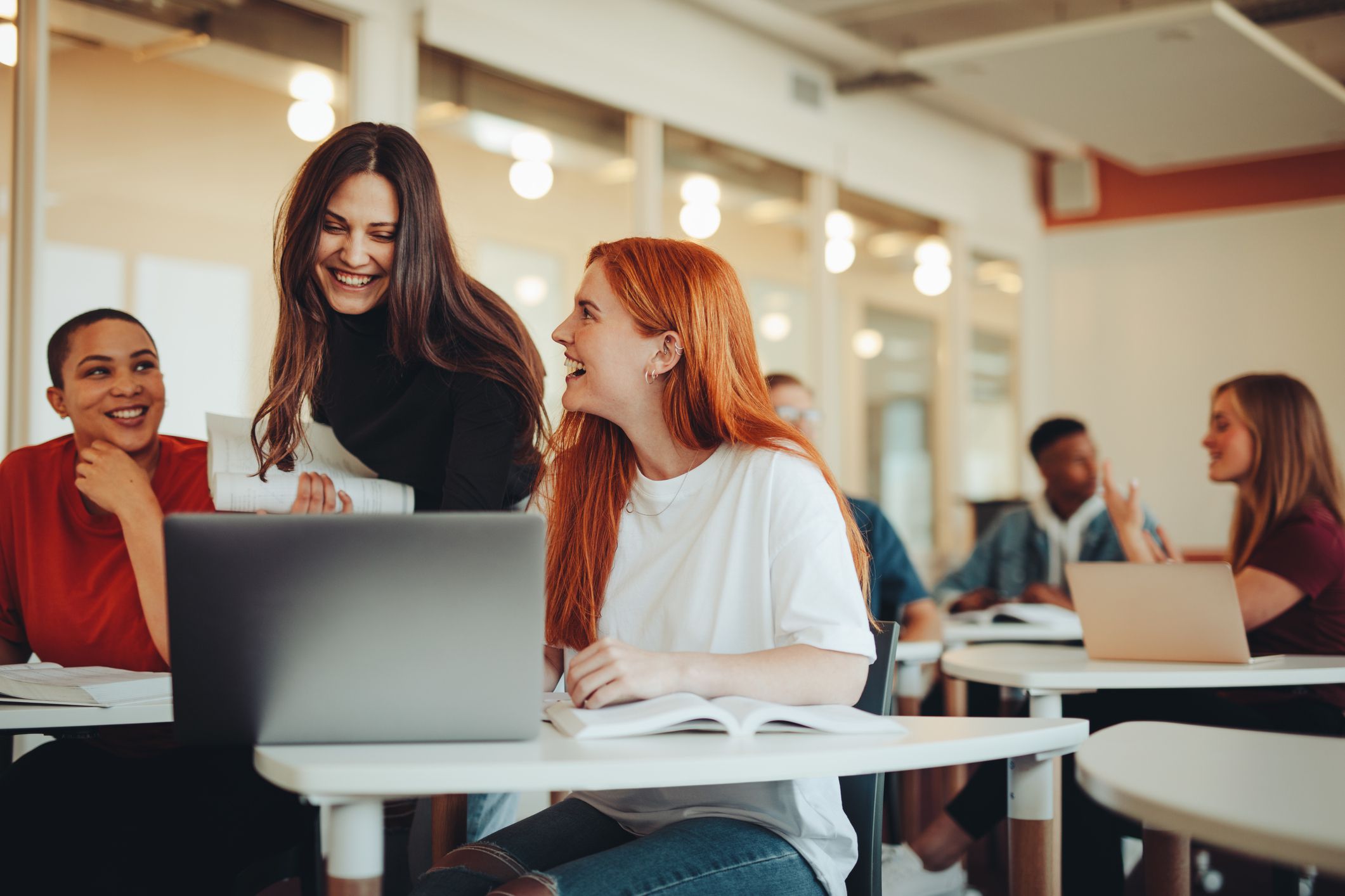College Students Working in Pairs With a Laptop Each, Female Professor Giving Feedback to One Pair, Smiling