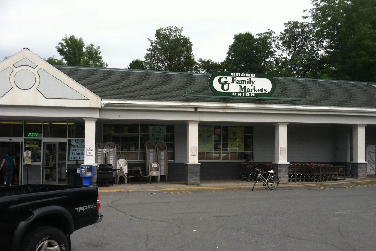 Front exterior of Grand Union Family Market, Bolton Landing, New York, driveway in the foreground, trees and a pale sky in the background