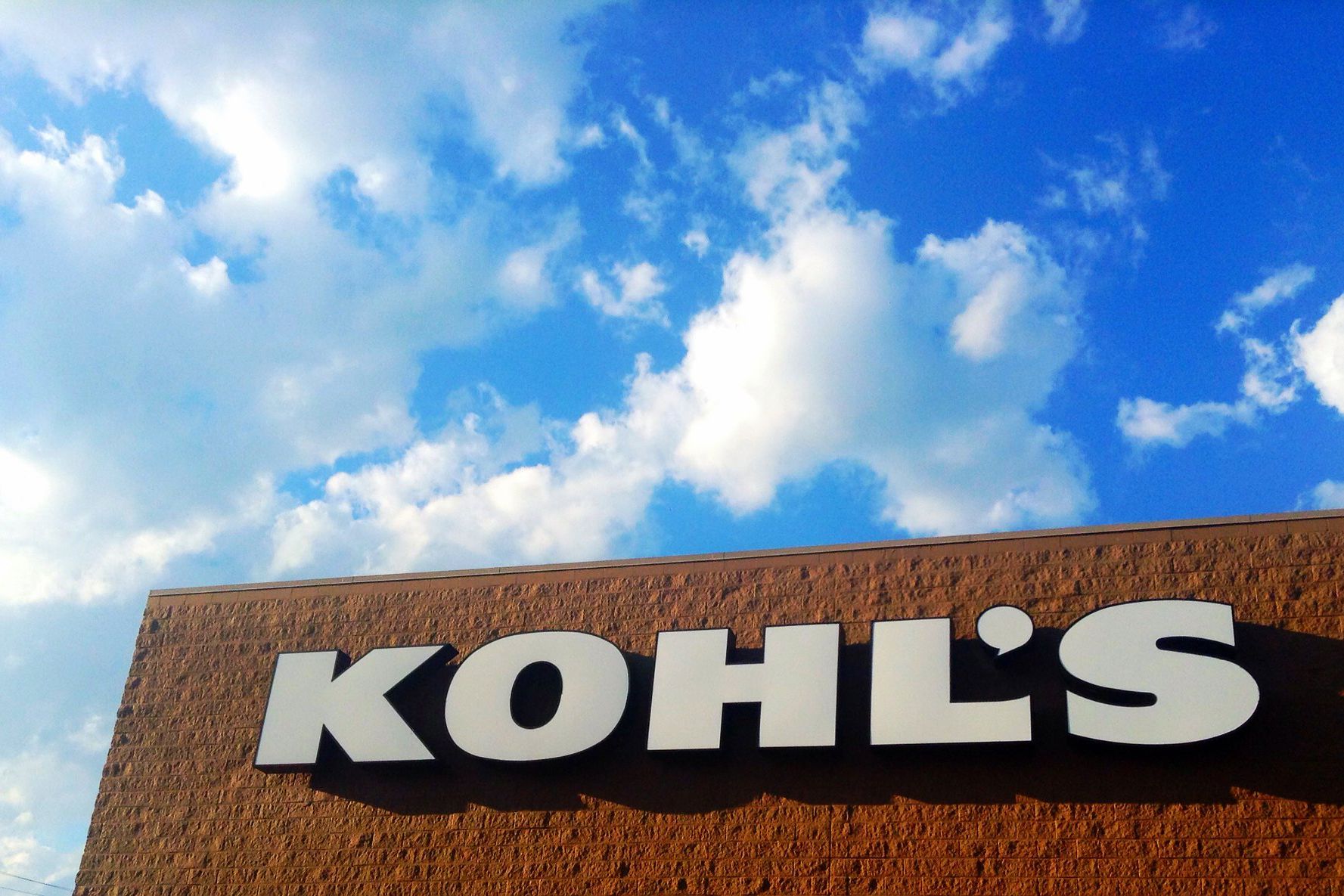 Kohl's logo on top of store, Plainville, Connecticut, brown building, against a blue sky with dramatic white clouds