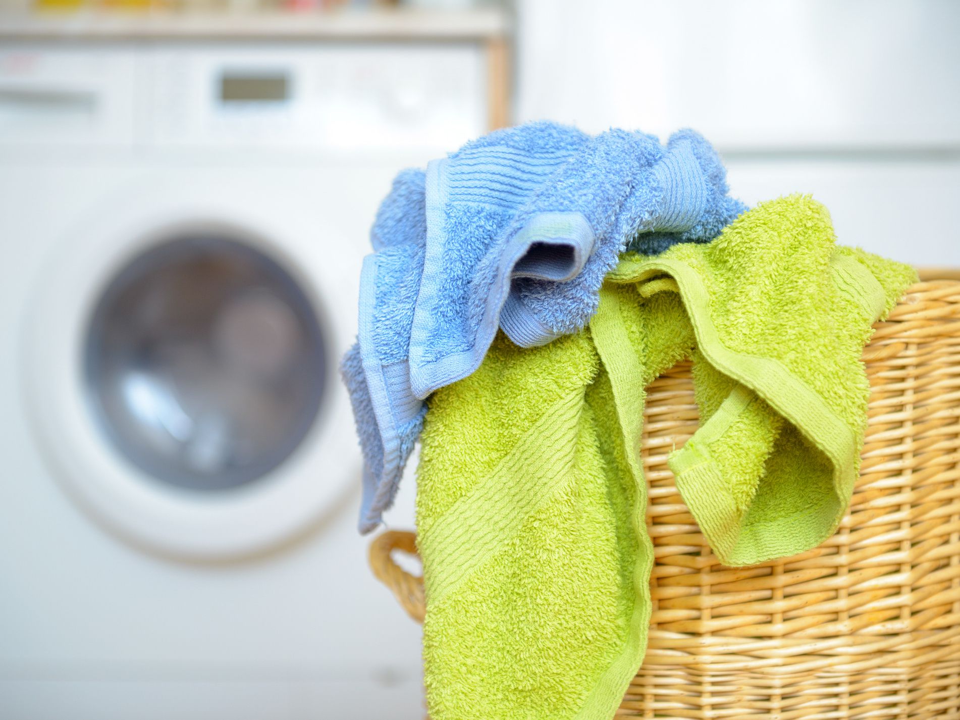 Dirty clothes basket with towels waiting for laundry with washing machine in backround