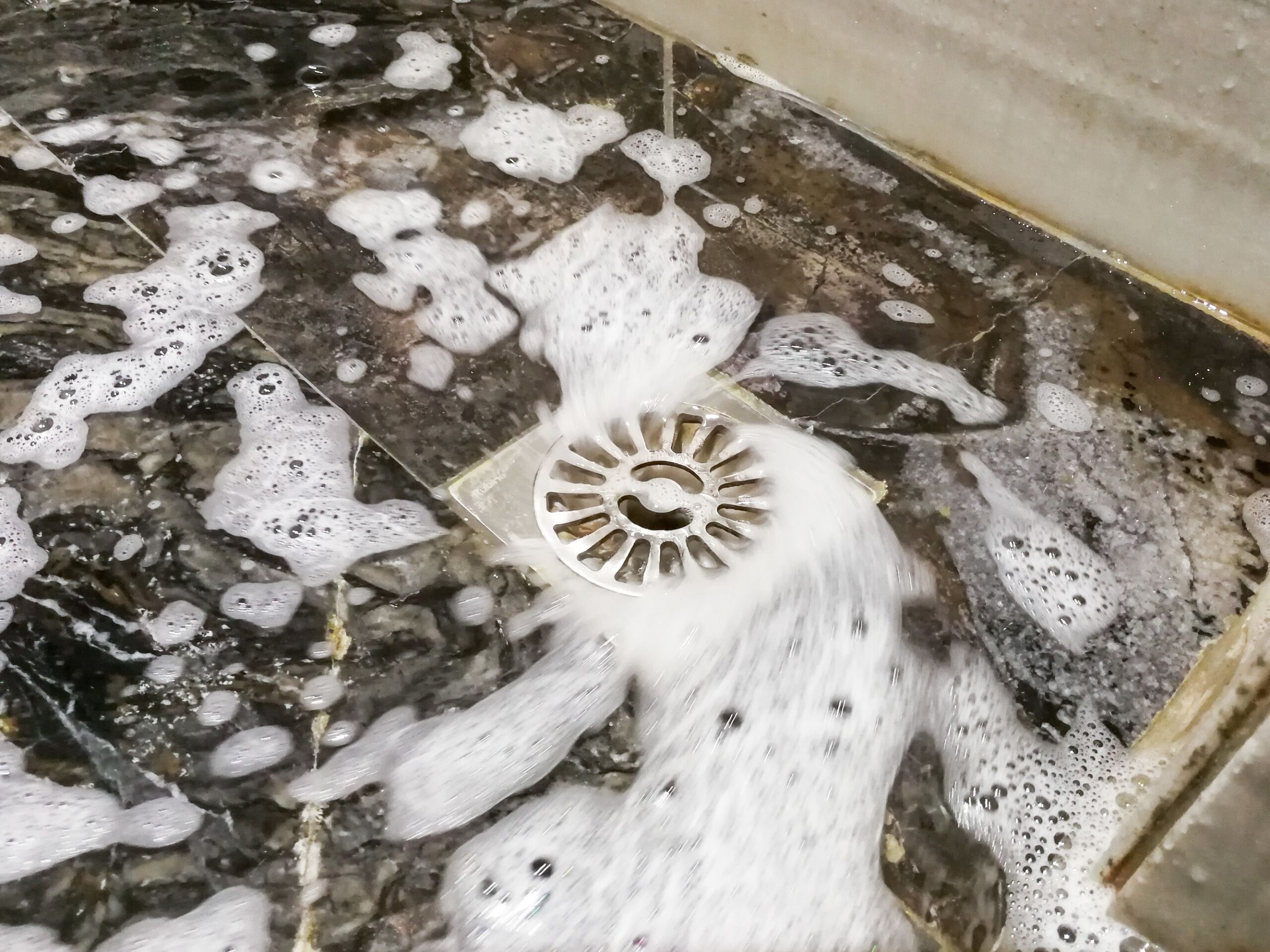 Soap foam suds and water flowing into bathroom drainage hole