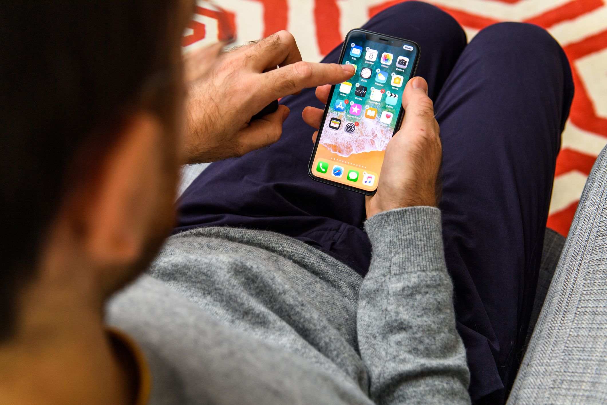 London: Man using the new Apple iPhone Xs with the immense OLED retina display and a12 bionic chip, looking over the app application delete apps from screen on his living room sofa