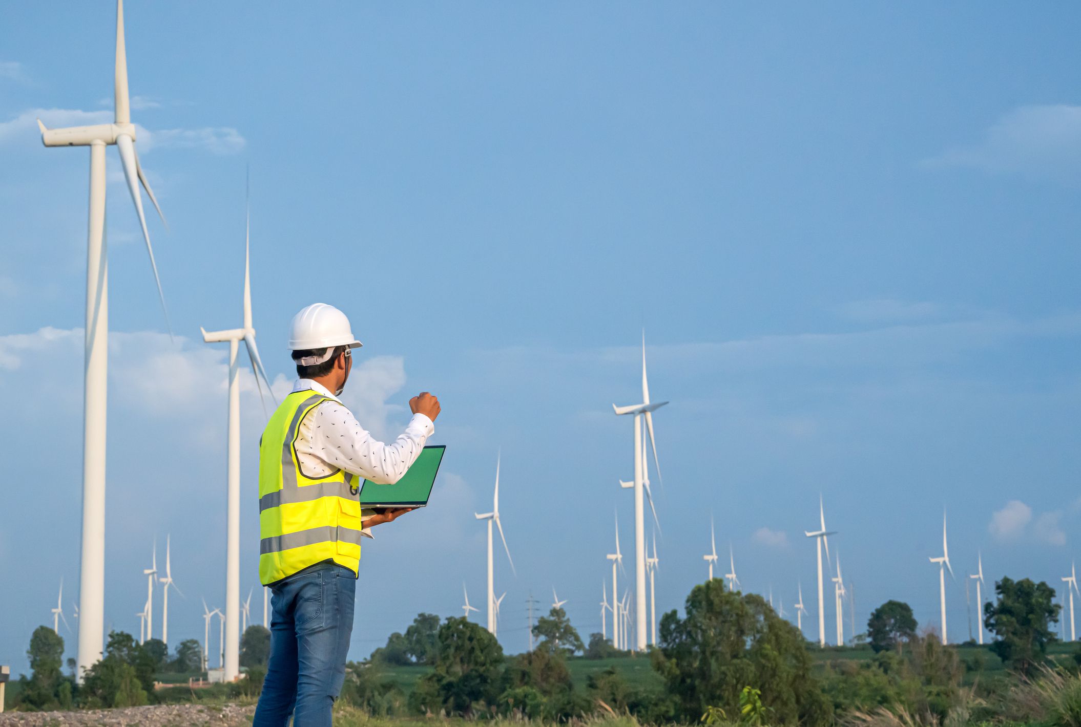 Wind Turbine Asian Mechanical Engineer working by laptop computer at Wind Turbine field,wind power and Alternative energy concept,Electric power industry.success happy pose