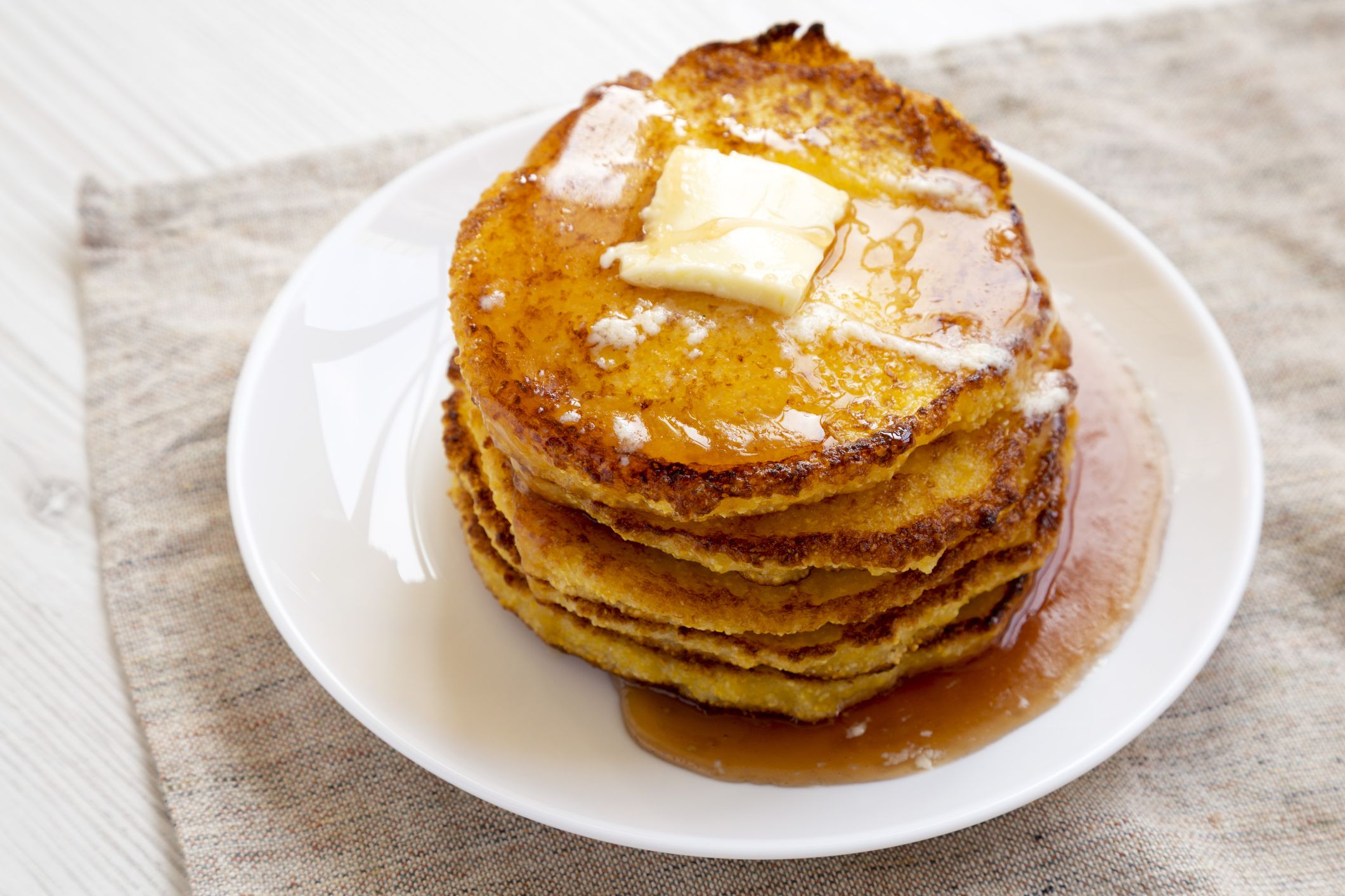 Homemade corn meal Johnny cakes on a white plate, side view. Close-up.