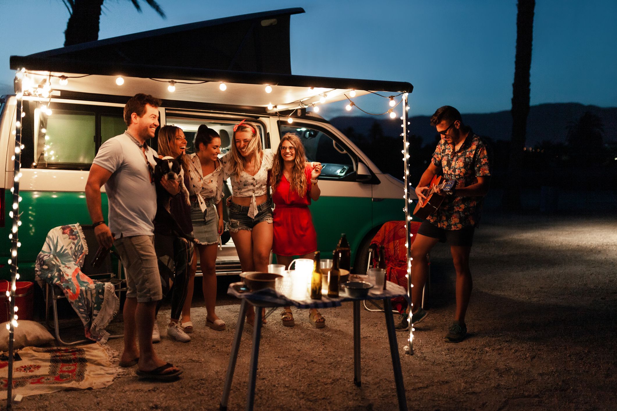 Party men are singing their friends at night near a camper van