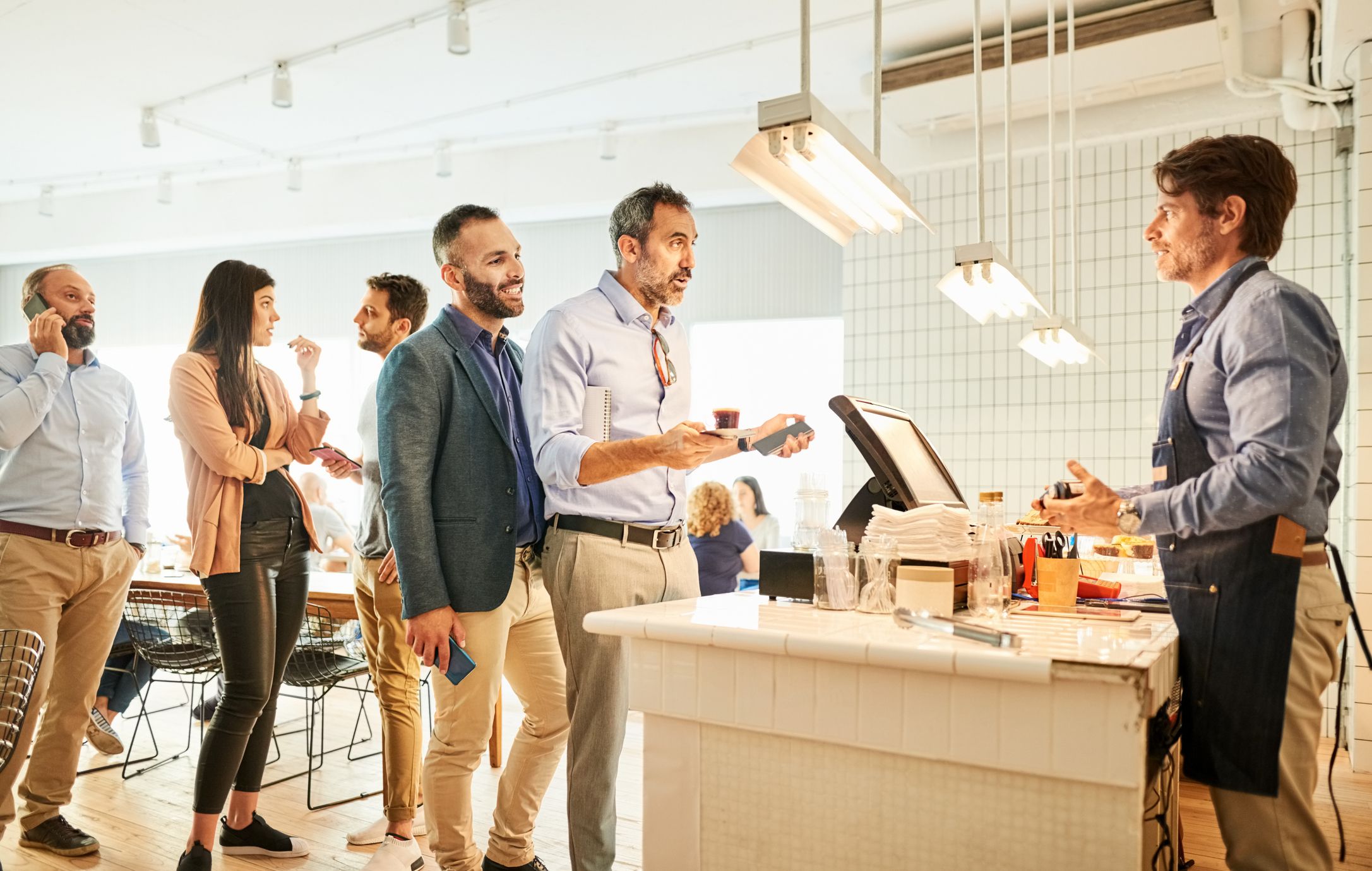People waiting in line at cafe counter for giving their order