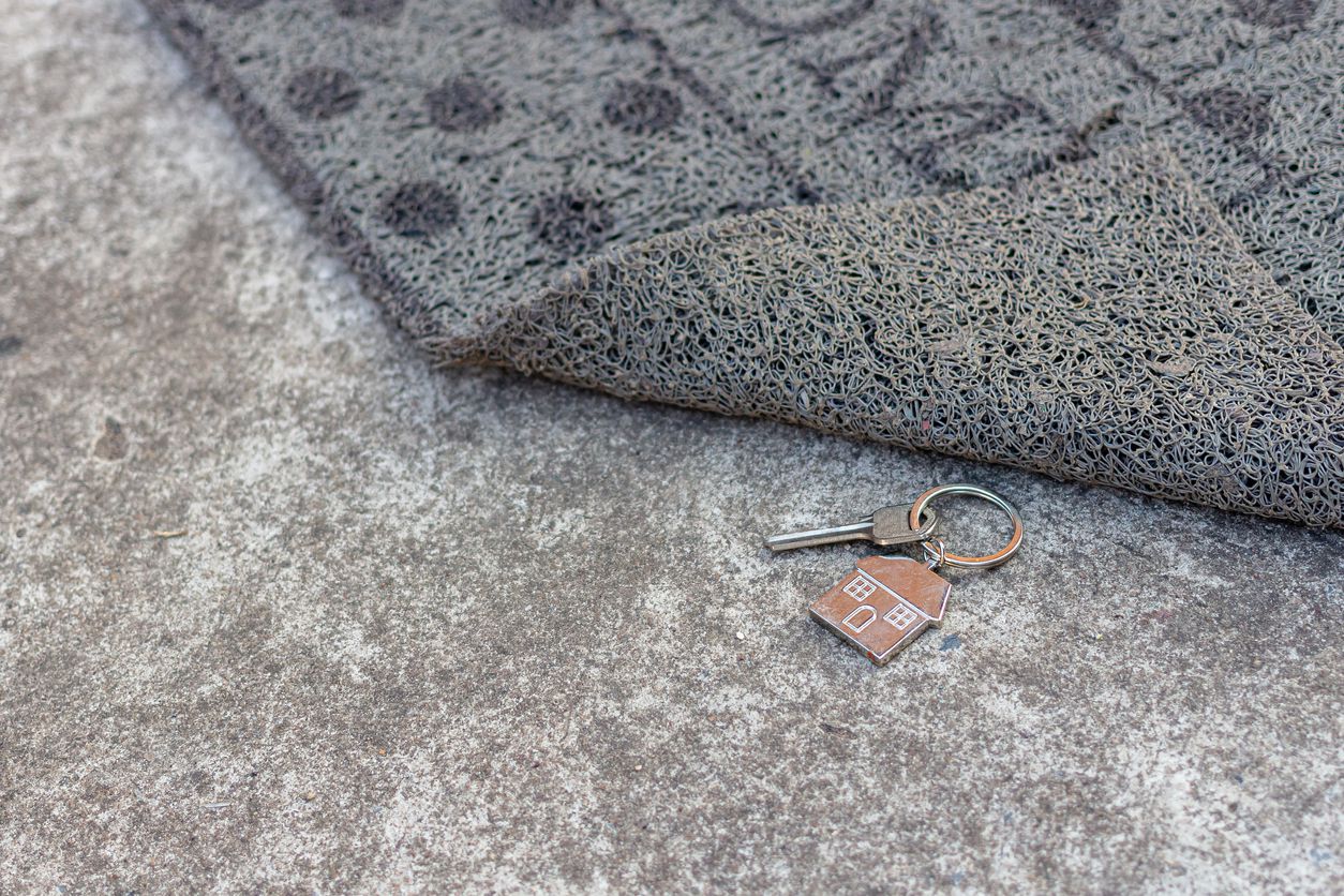 An image of keys placed under a doormat.