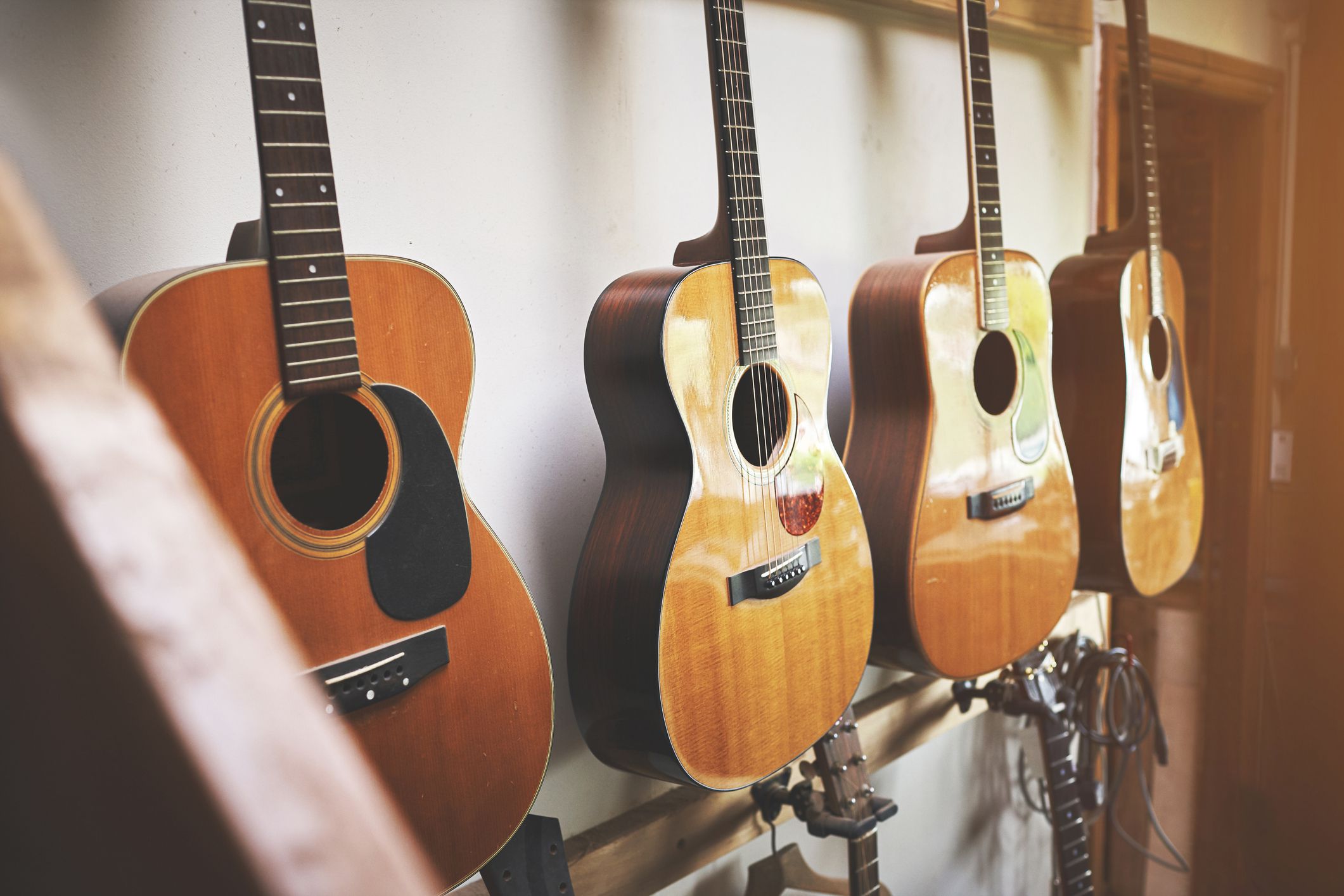 Group of classic musical guitar instruments on display in a music shop. Classical vintage acoustic guitars of a instrument made from art wood hanging on a rack in a new indoor local store.