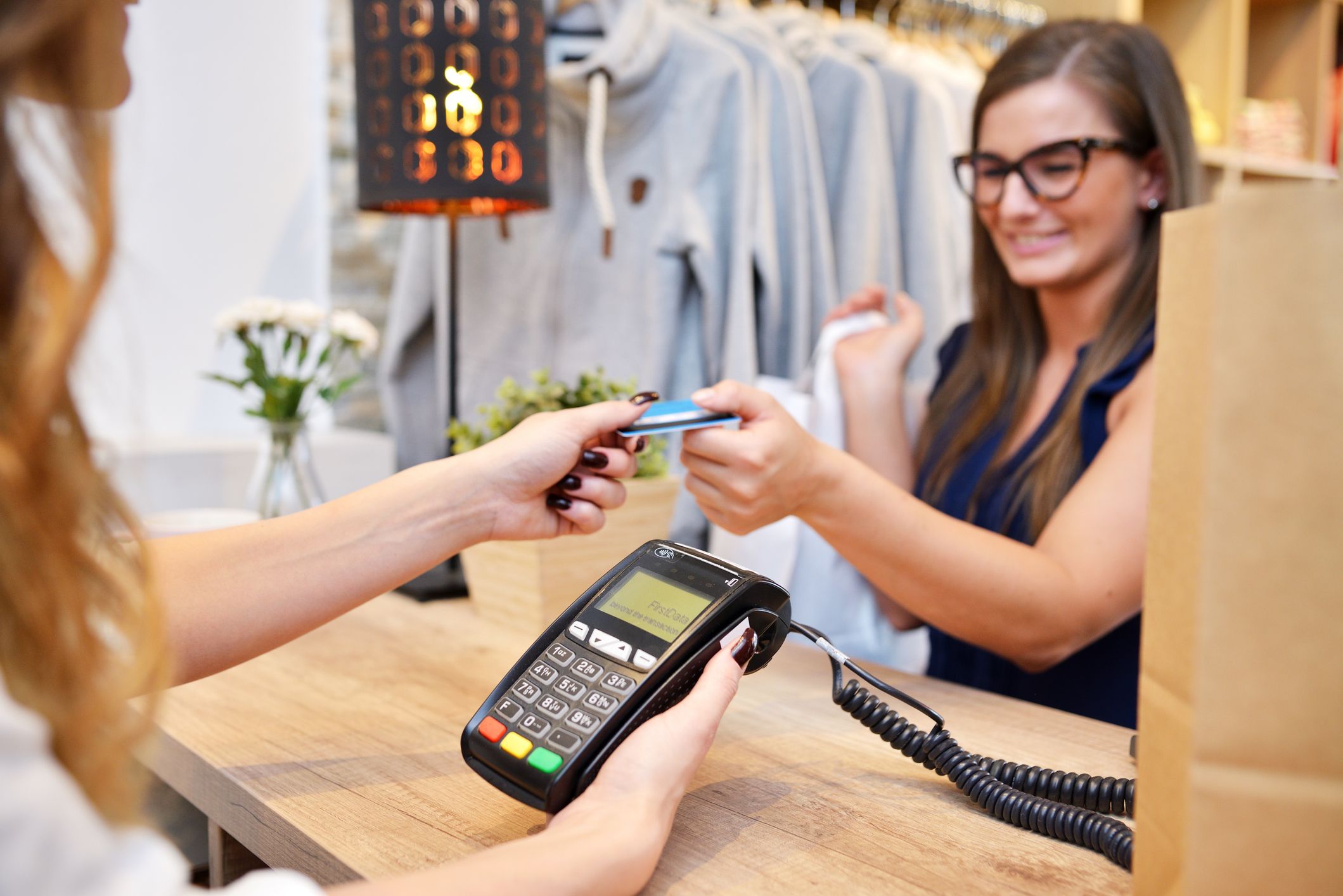 Young woman happily shopping in a women's fashion boutique. Paying for the cashier.