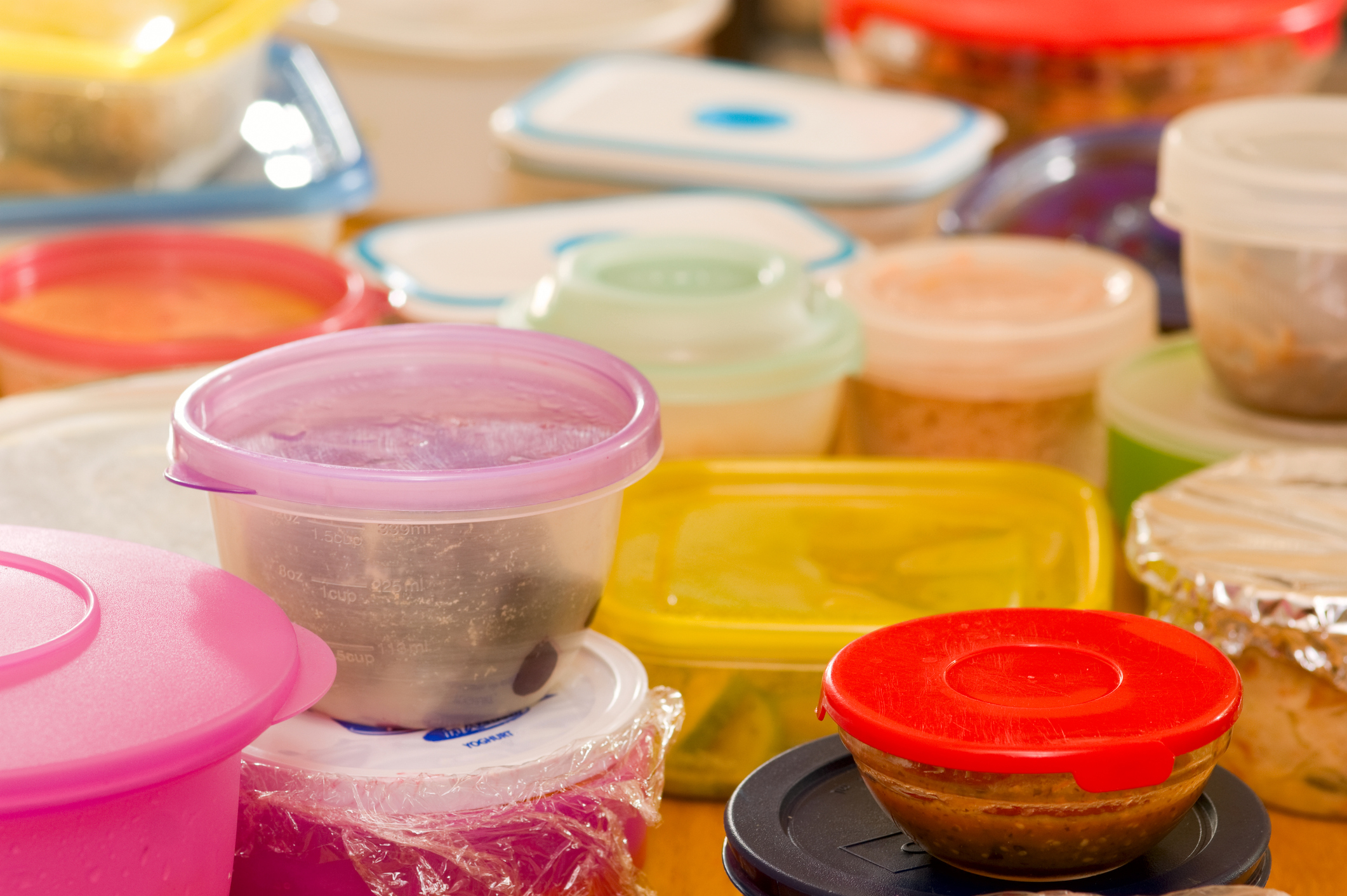 Numerous Food Storage Containers With Leftovers Scattered on a Table
