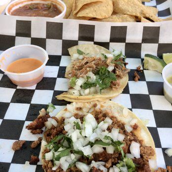 three tacos on a checked tablecloth