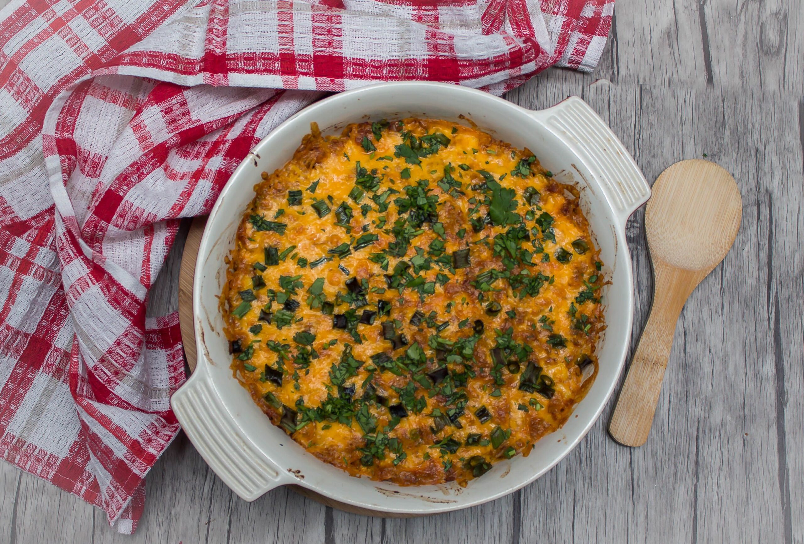 Baked Mexican Casserole on a wooden table with a white and red checkered towel