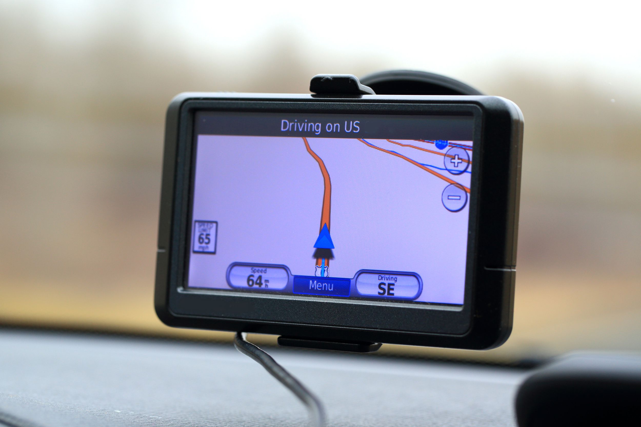 Closeup of GPS device mounted to window of car with blurred background of car interior and outside of front window