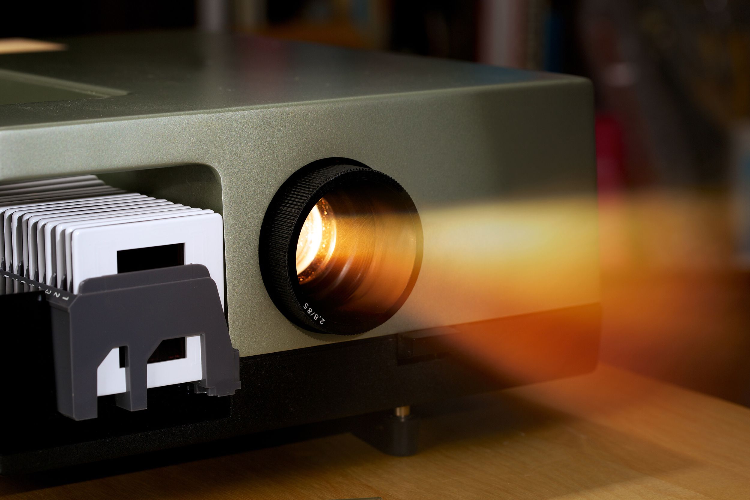 Closeup of projector shining orange bright light beam in dark background