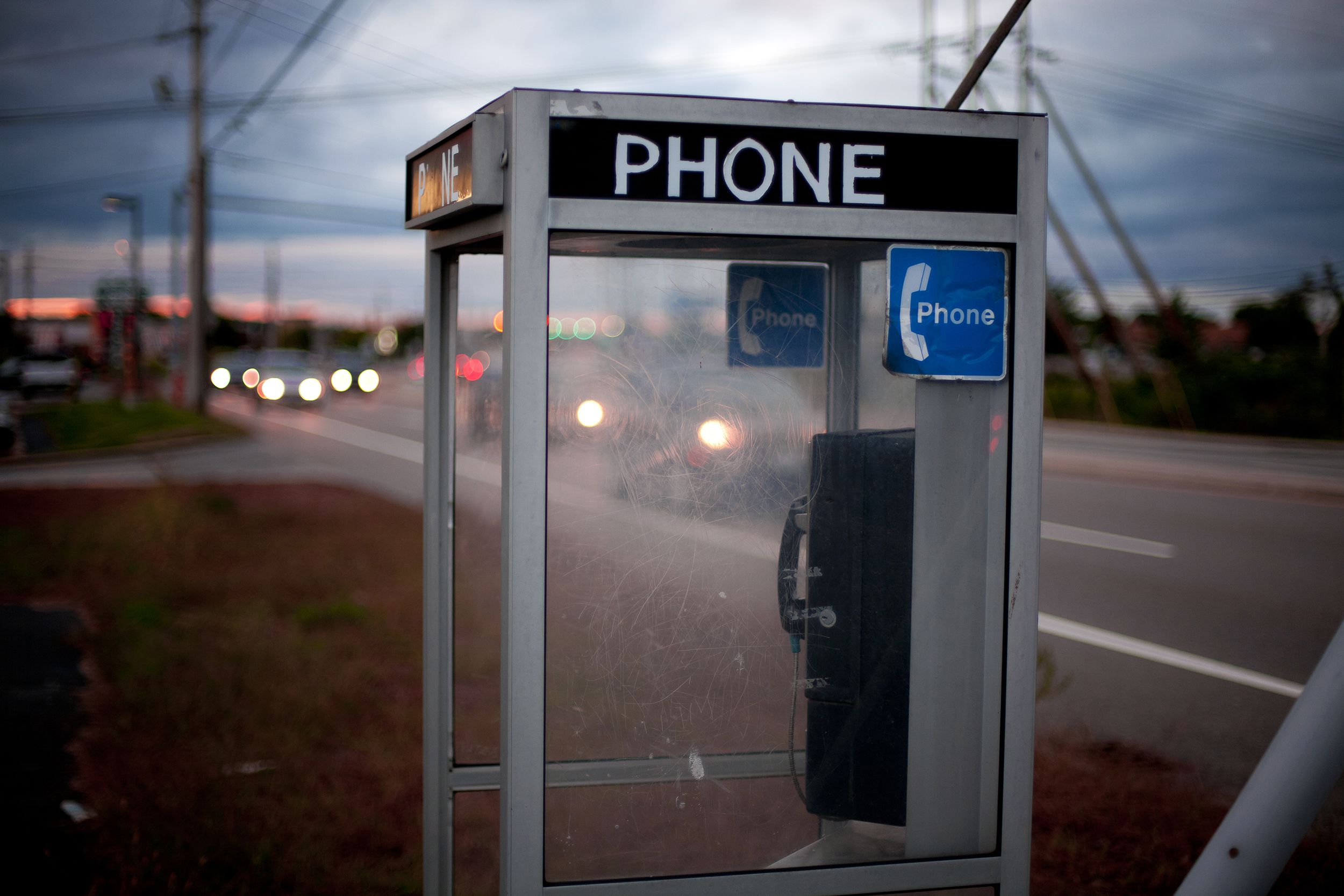 Closeup of an empty telephone booth along a highway in America with a blurred background of the highway and sunset