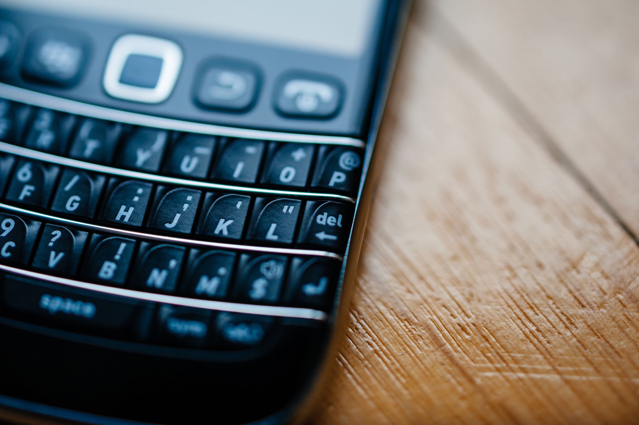 Closeup of the keyboard of a vintage Blackberry with blur on a wooden table