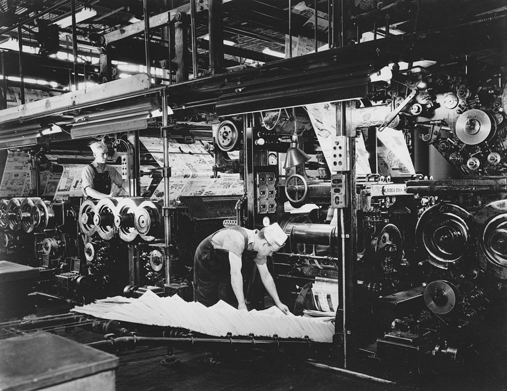 Workers on a newspaper printing press circa 1940.