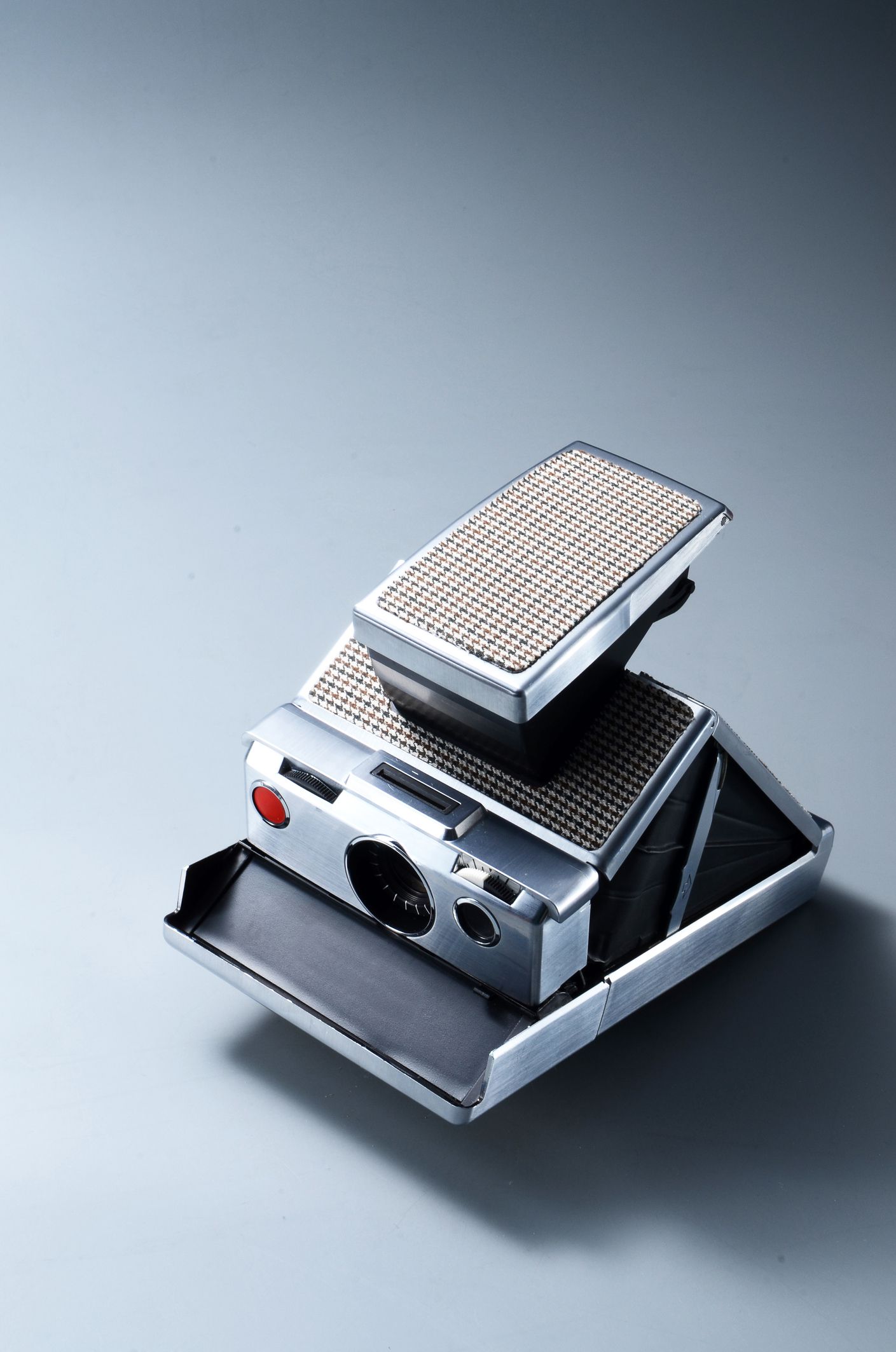 Grey vintage Polaroid SX-70 camera on a steel grey background