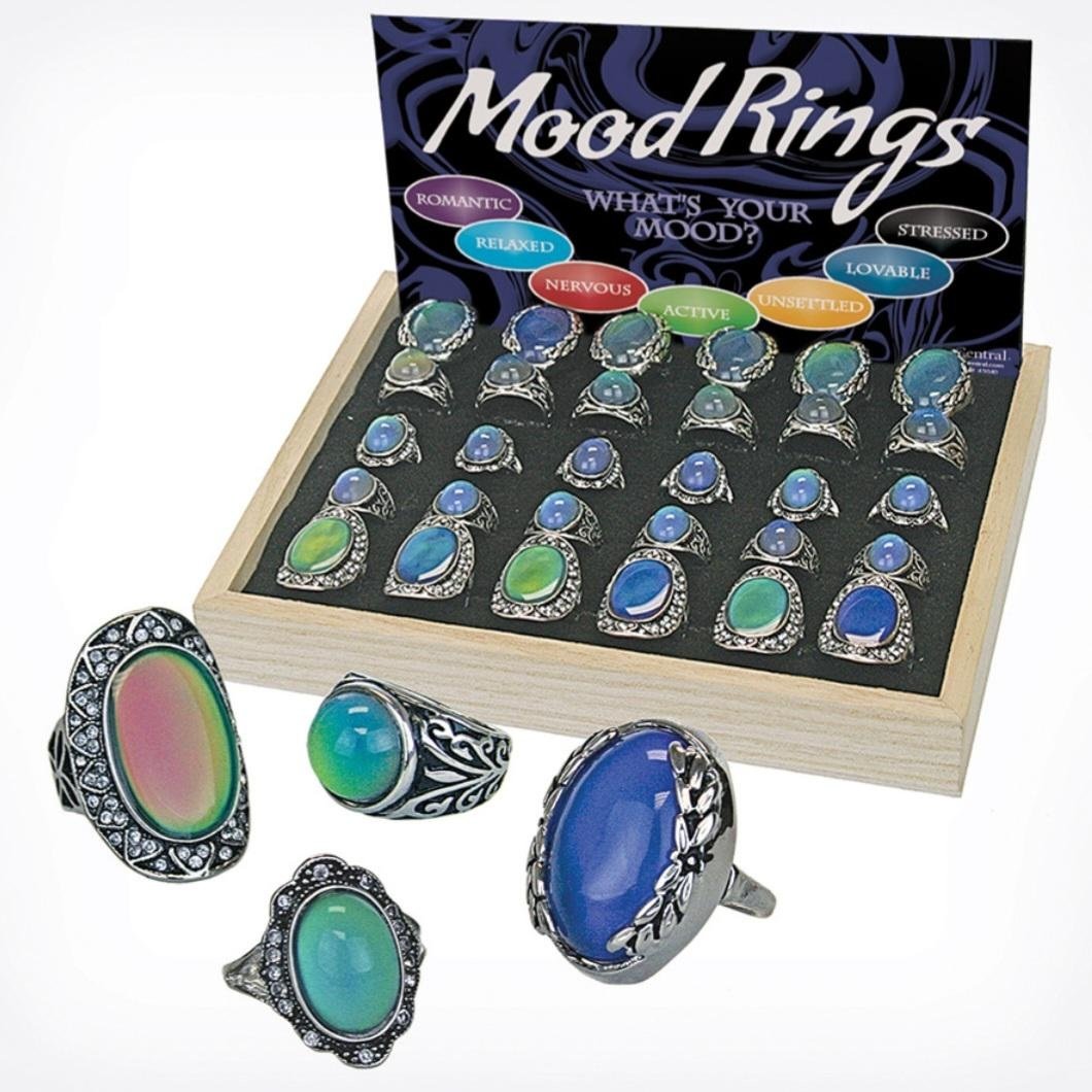 A display box of mood rings with colorful stones, arranged in rows. The sign reads "Mood Rings: What's Your Mood?" with color meanings like romantic, relaxed, nervous, active, unsettled, stressed, and lovable. Four rings are in front.