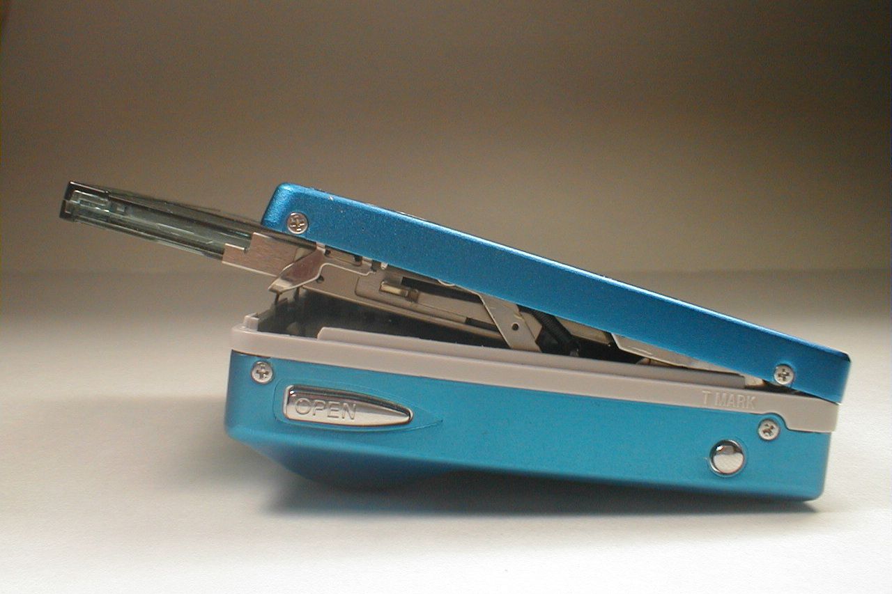 Side view of a blue MiniDisc player ejecting a MiniDisc with a grey gradient background