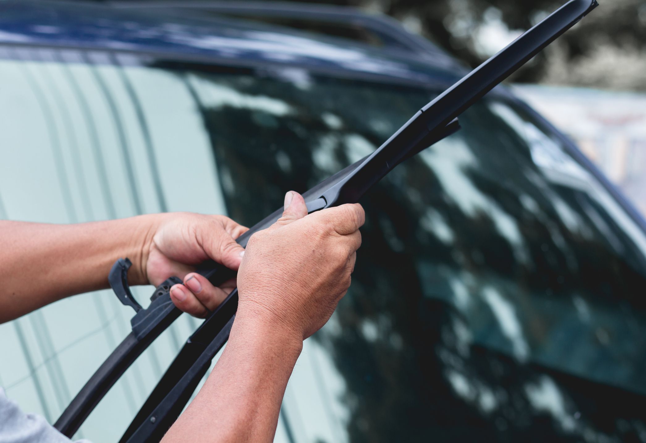 Mechanic replace windshield wipers on car. Replacing wiper bladesChange cars wiper blades. Technician Man changing windshield wipers blades on car.