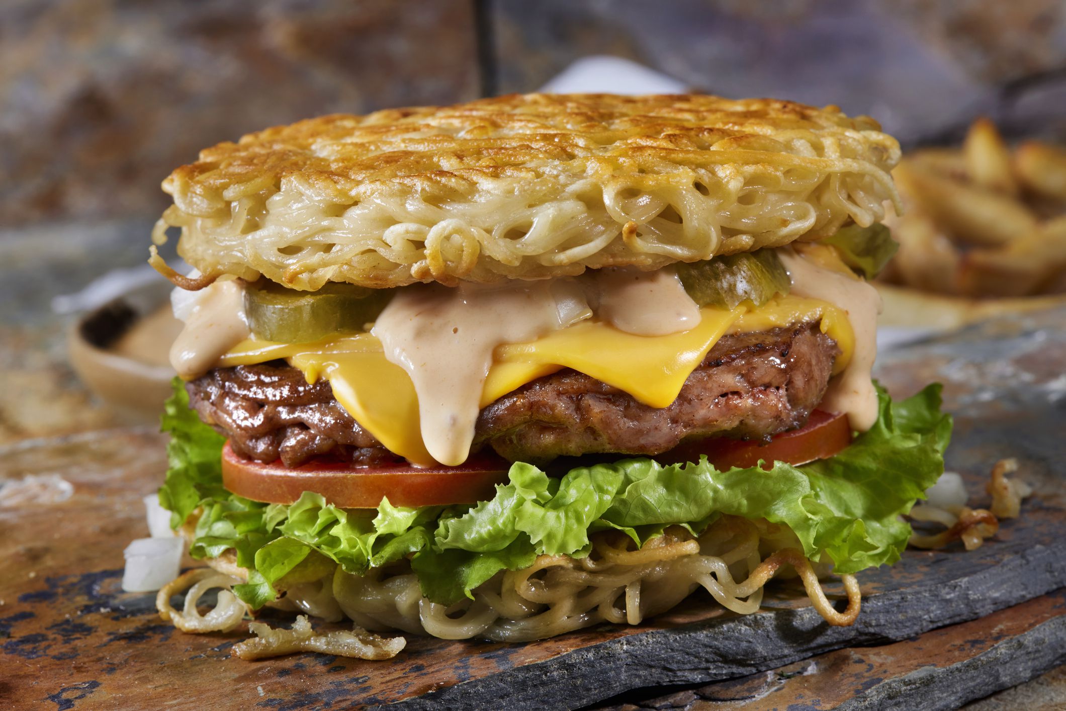 The Fried Ramen Bun Cheeseburger with Lettuce, Tomato, Onions, Pickles, Spicy Mayo and Fries