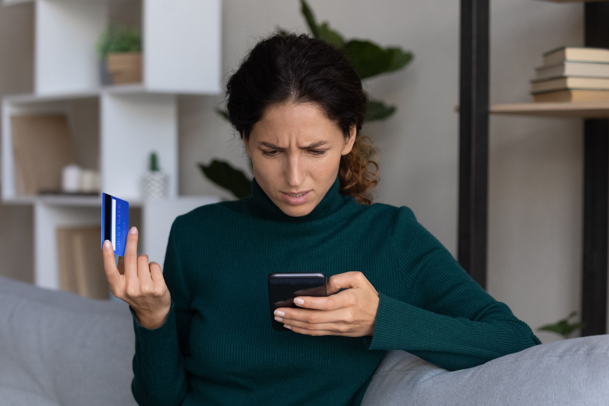 Internet scam. Concerned young hispanic lady looking on smartphone screen having finance savings stolen from bank card as money fraud result. Upset nervous latin woman become online scammers victim
