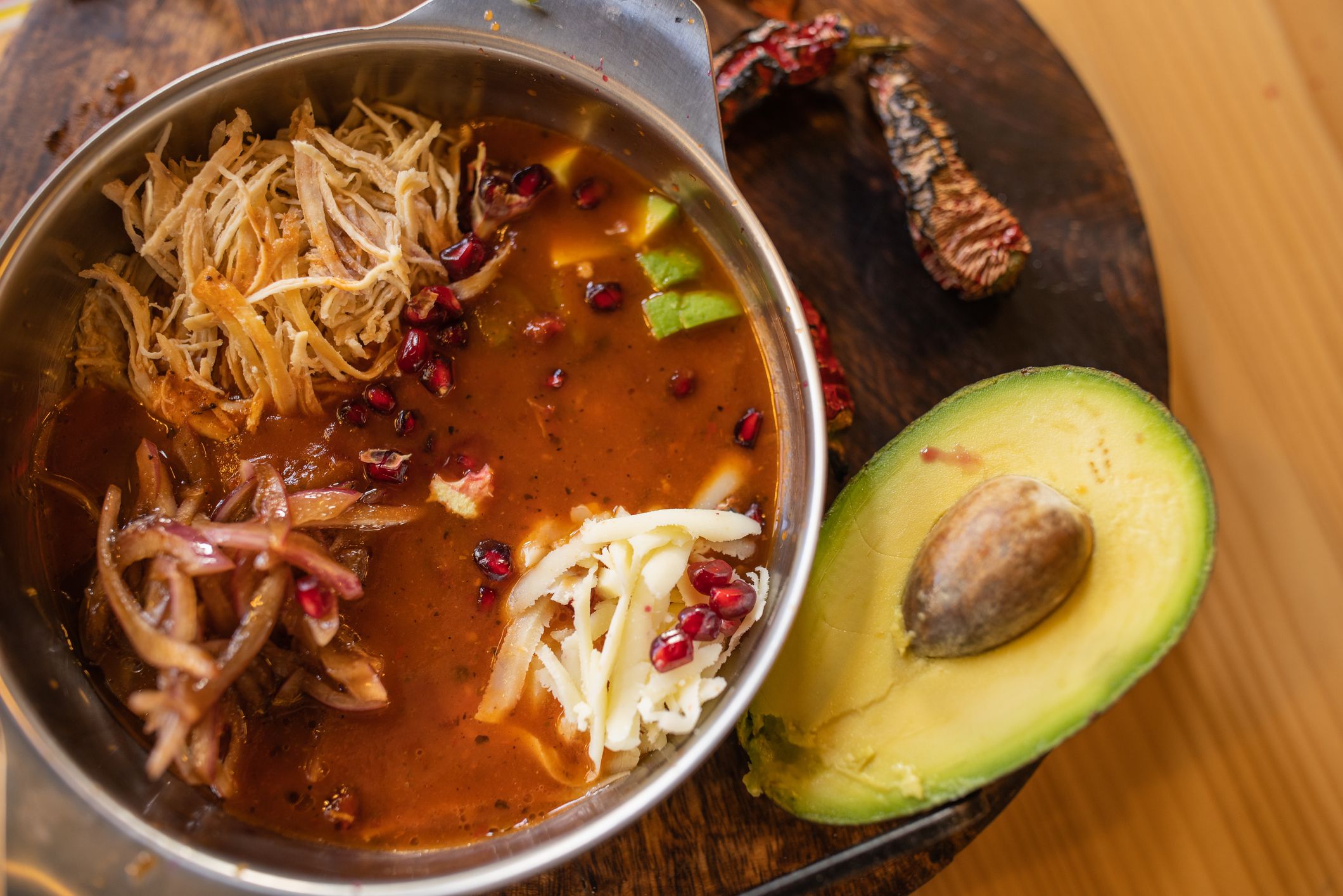 Exotic mexican soup, with pomegranate, chicken meat, onion and cheese