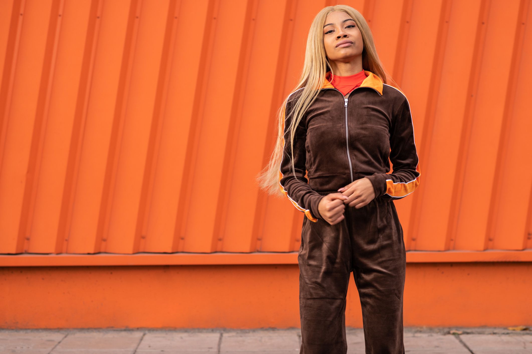 A young African American woman with long blonde hair and sportswear on an orange background