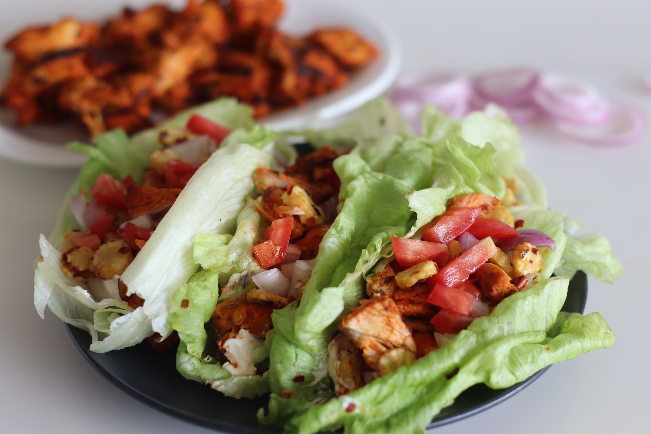 Lettuce chicken wrap. Tandoori chicken bites, sauteed baby corn, fresh cut tomatoes and onions tossed and wrapped in iceberg lettuce leaves. Shot on white background