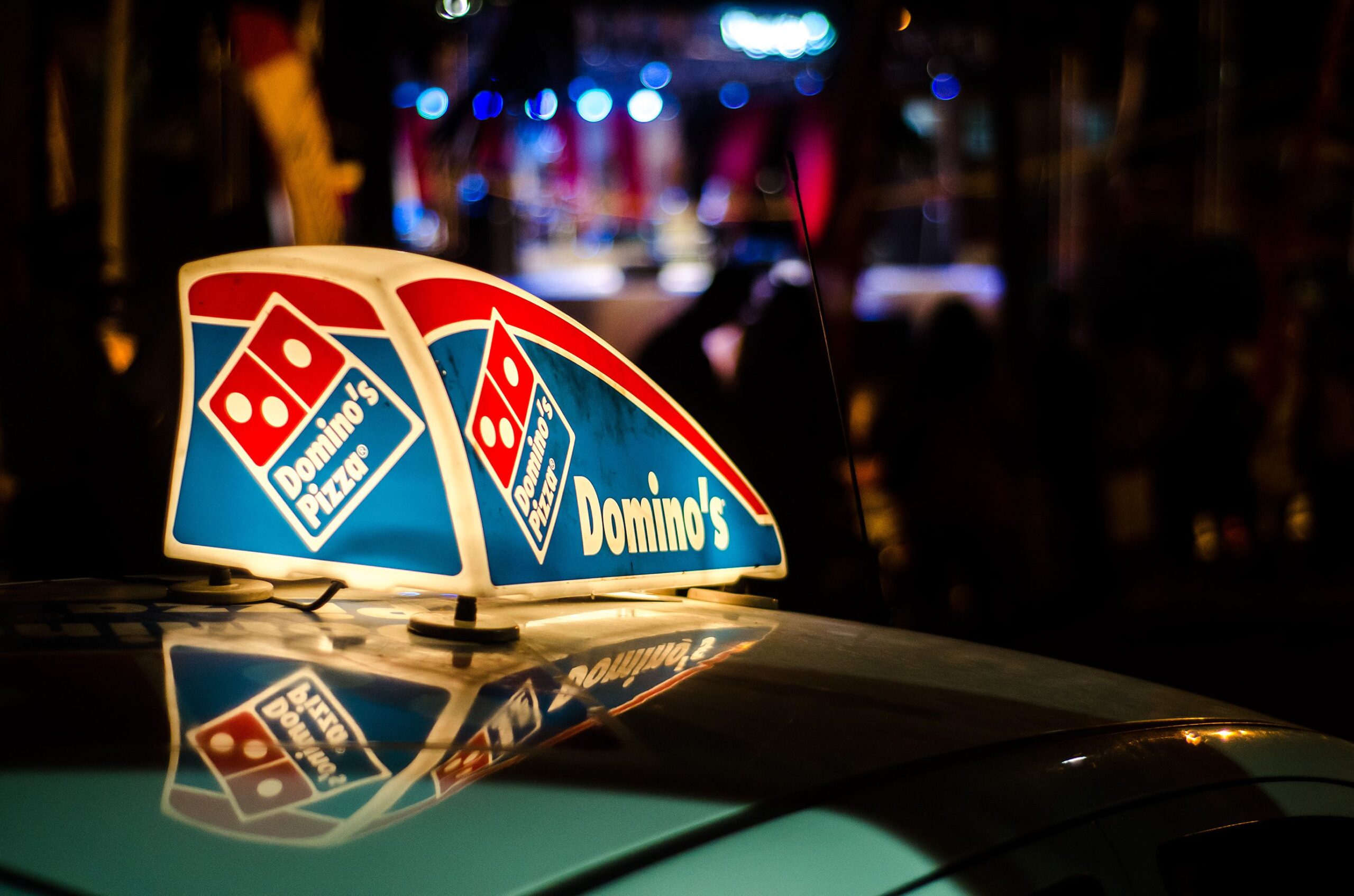 Gros Islet, St. Lucia - May 5, 2015: A Dominos Pizza vehicle is in the night street in Gros Islet district with a sign on its roof advertising the company and showing its trademark logo.