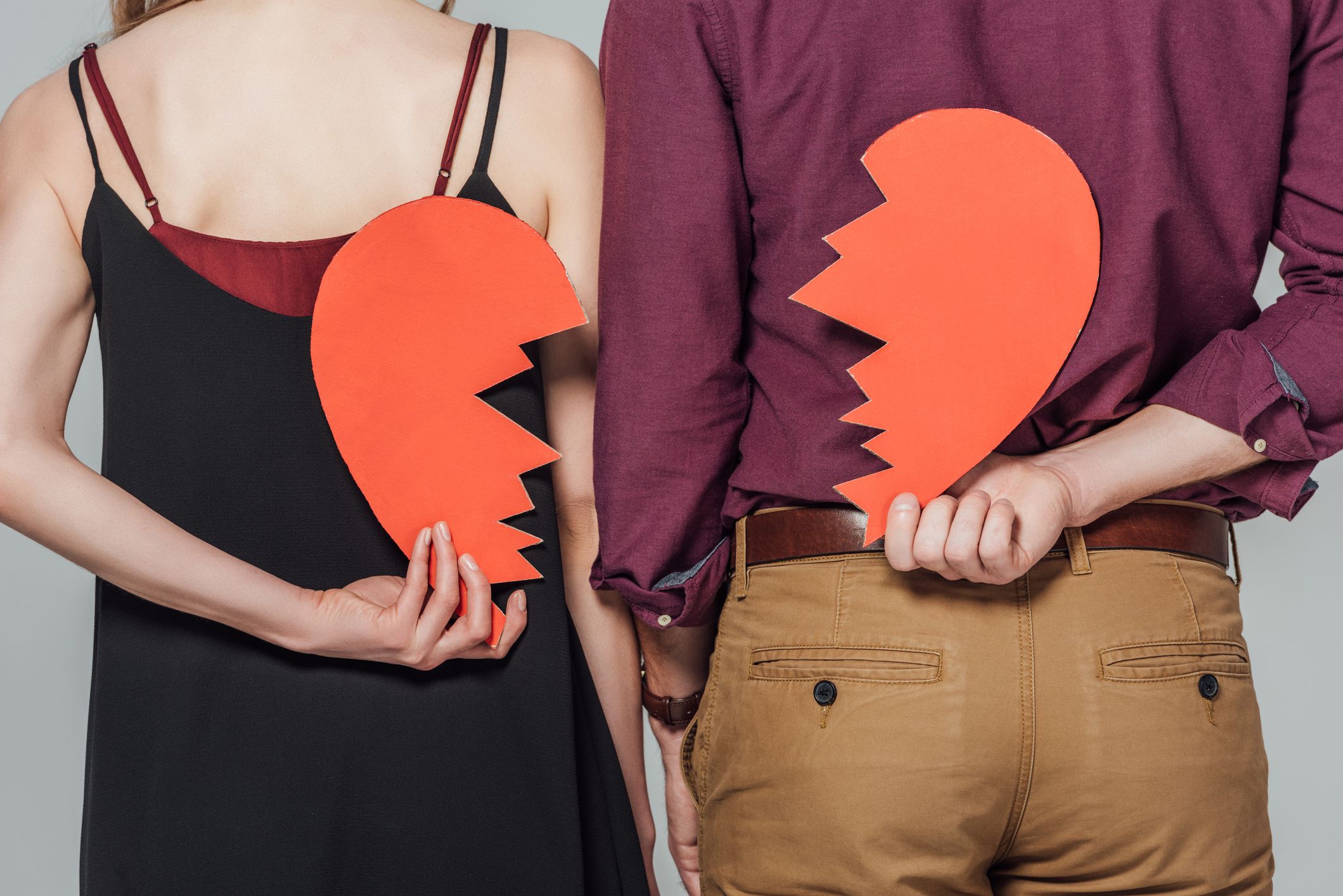 cropped shot of young couple holding broken heart symbol isolated on grey