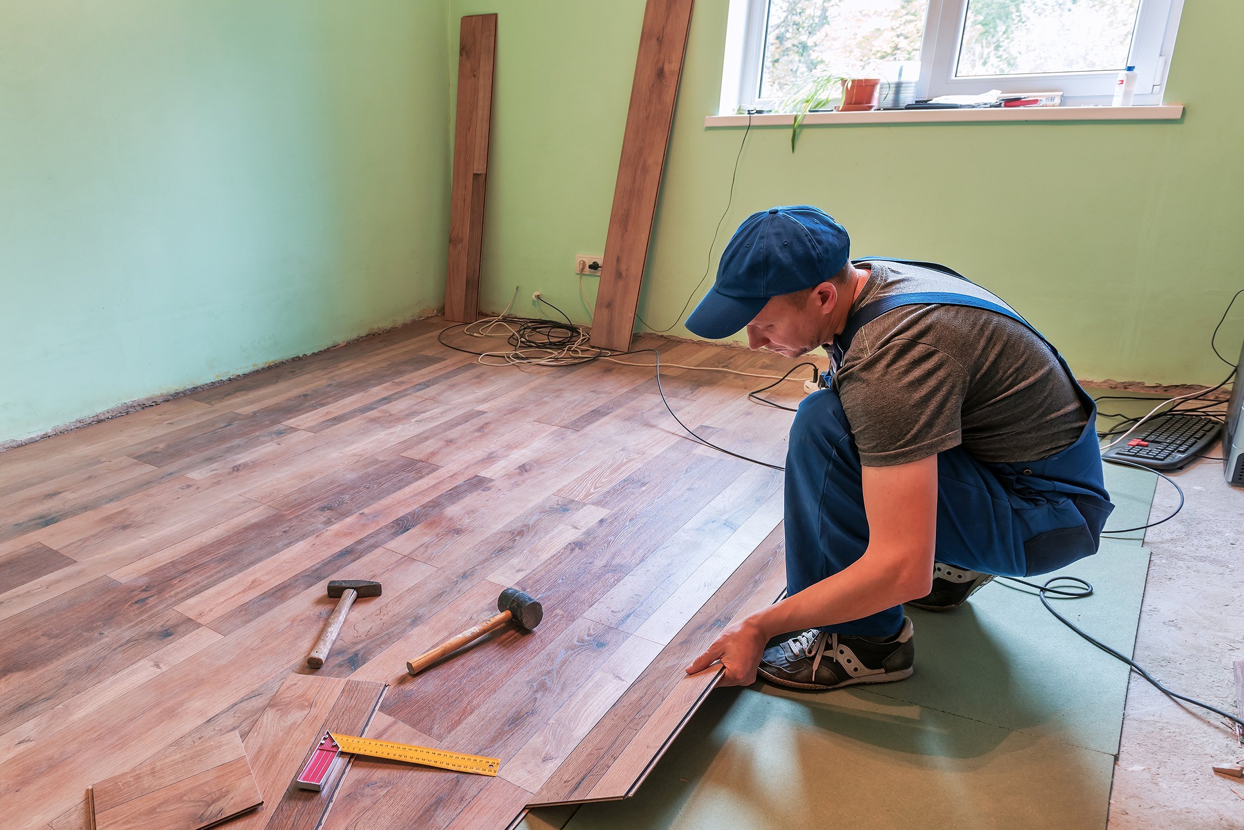 man laying wooden floor to room