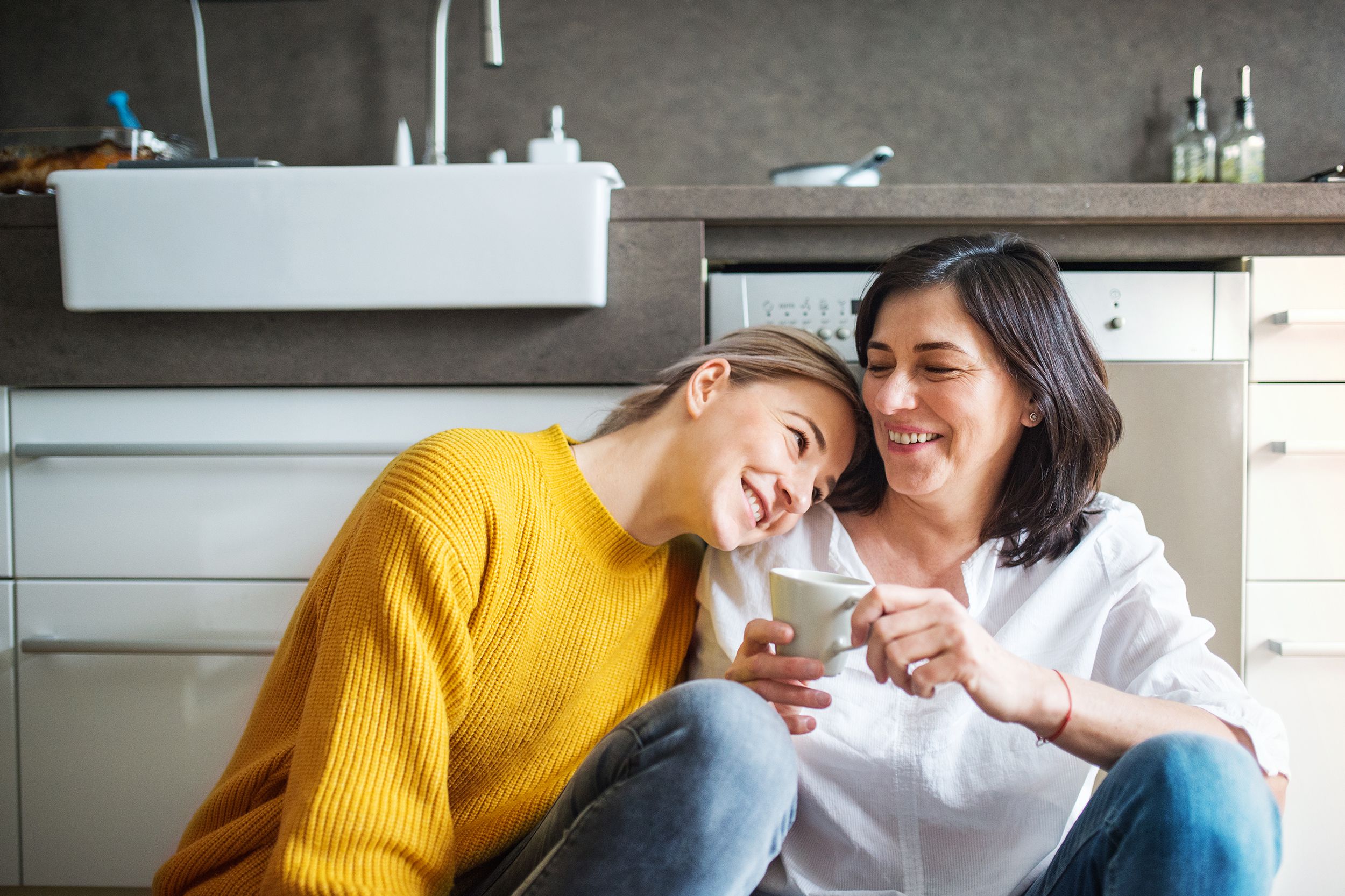 happy senior woman with and adult daughter in the kitchen