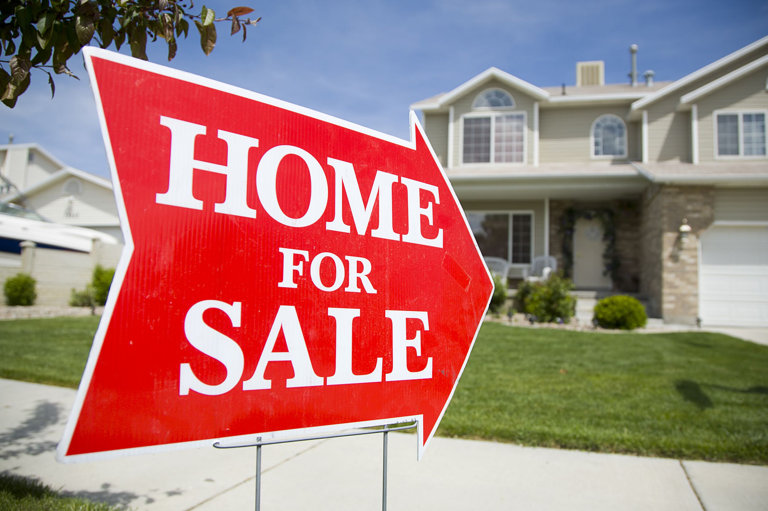 arrow shaped home for sale sign in front of large home
