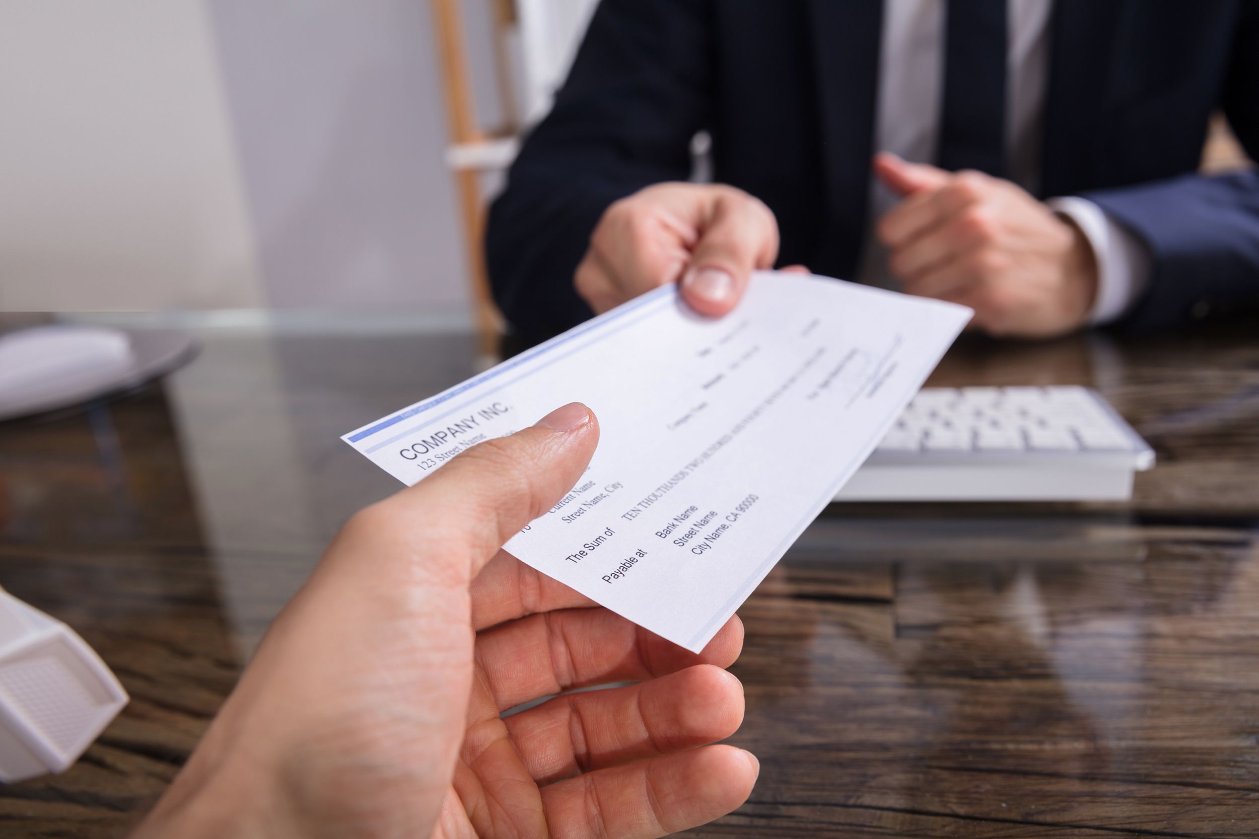 businessperson giving cheque to employee