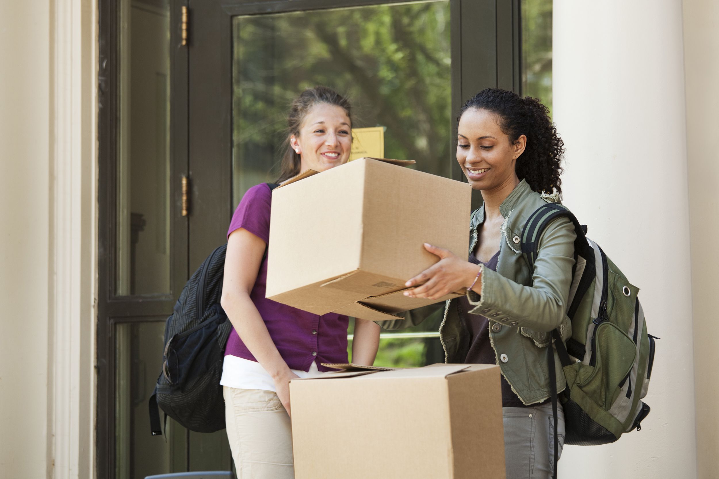 university students moving boxes outside of dorm on campus
