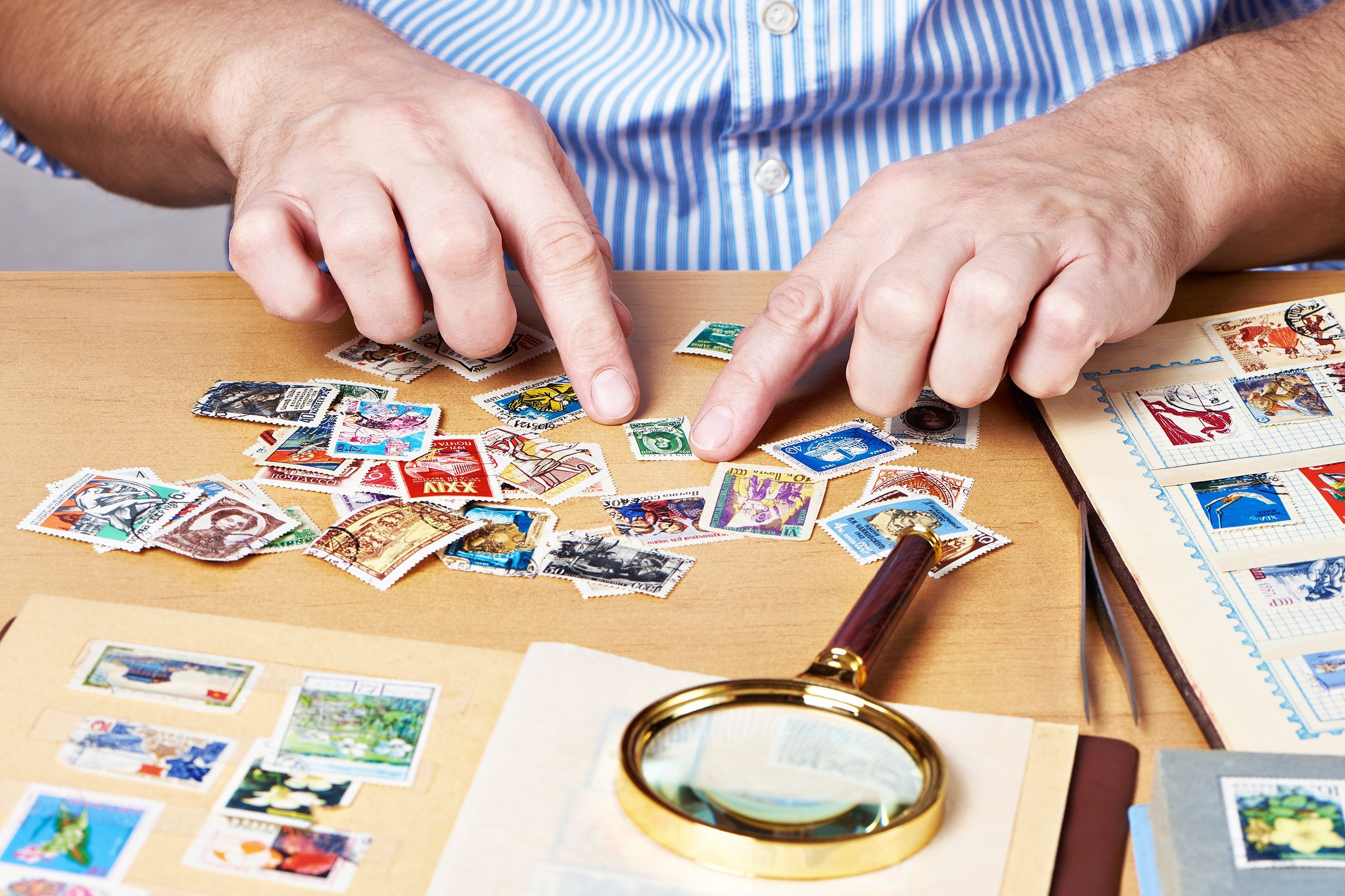 man watching a collection of postage stamps