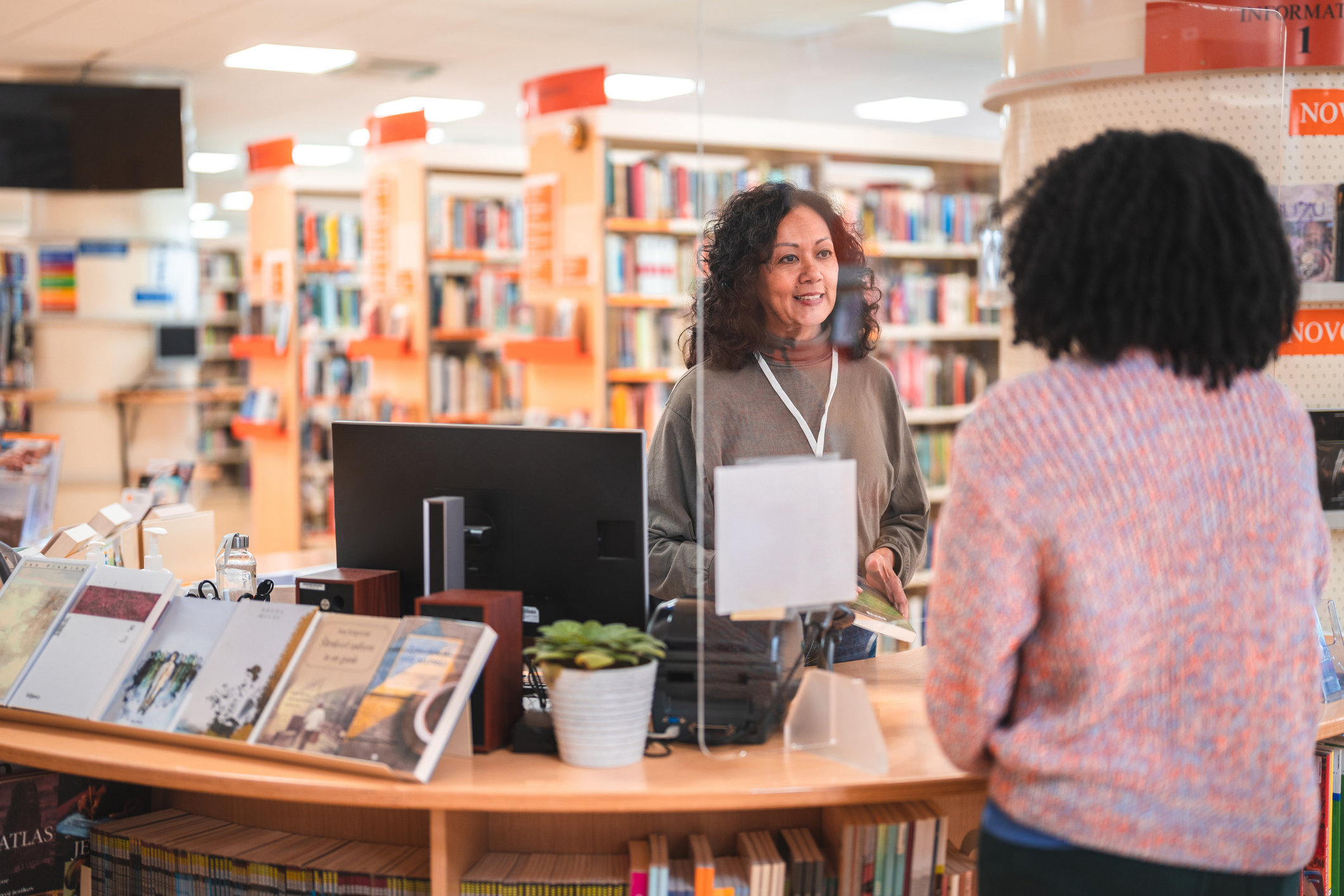 Woman Talking to Librarian at the Desk in a Public Library