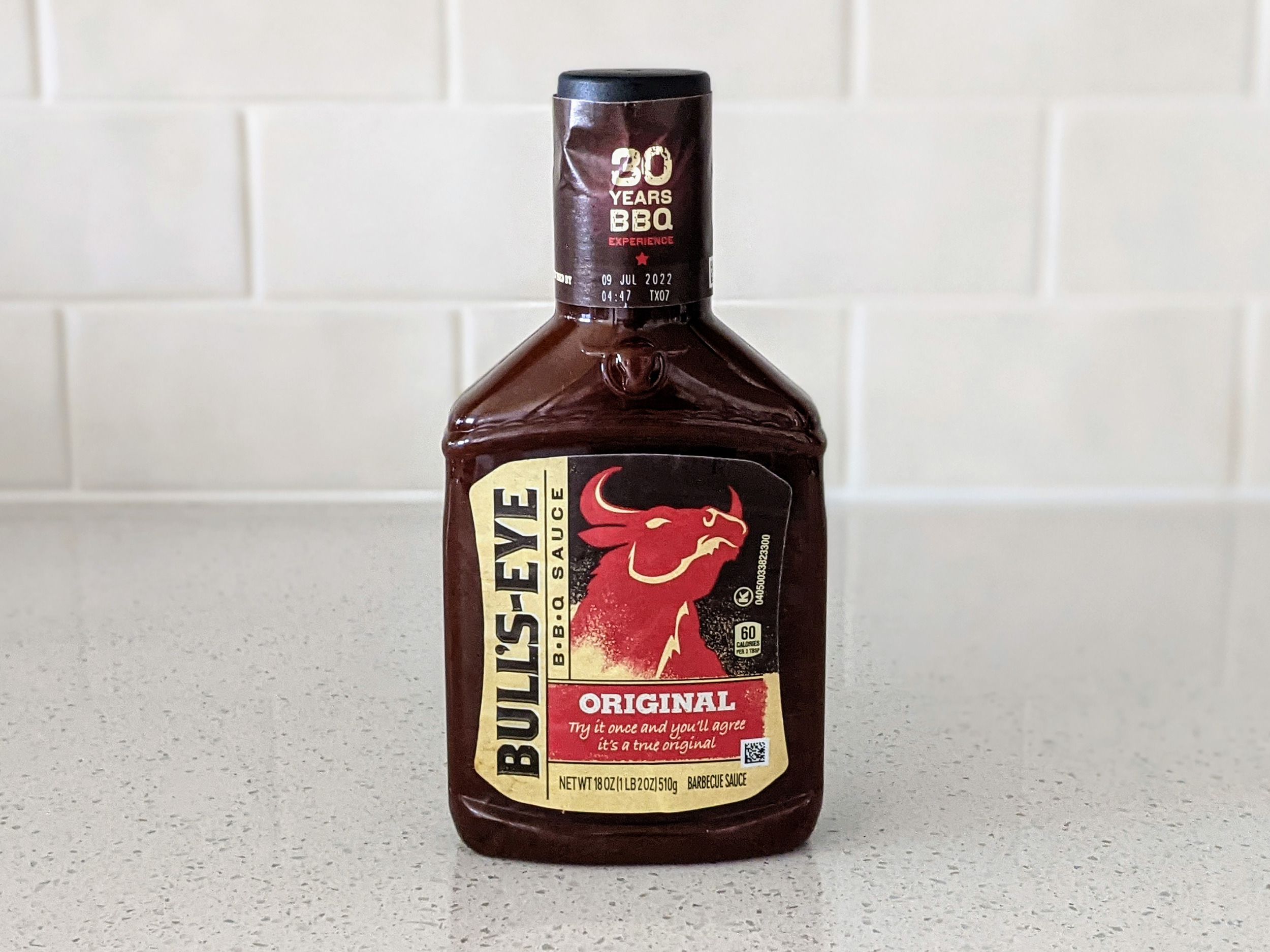 A Bottle of Bull’s Eye Original BBQ Sauce on a beige countertop, beige kitchen wall tile in the background