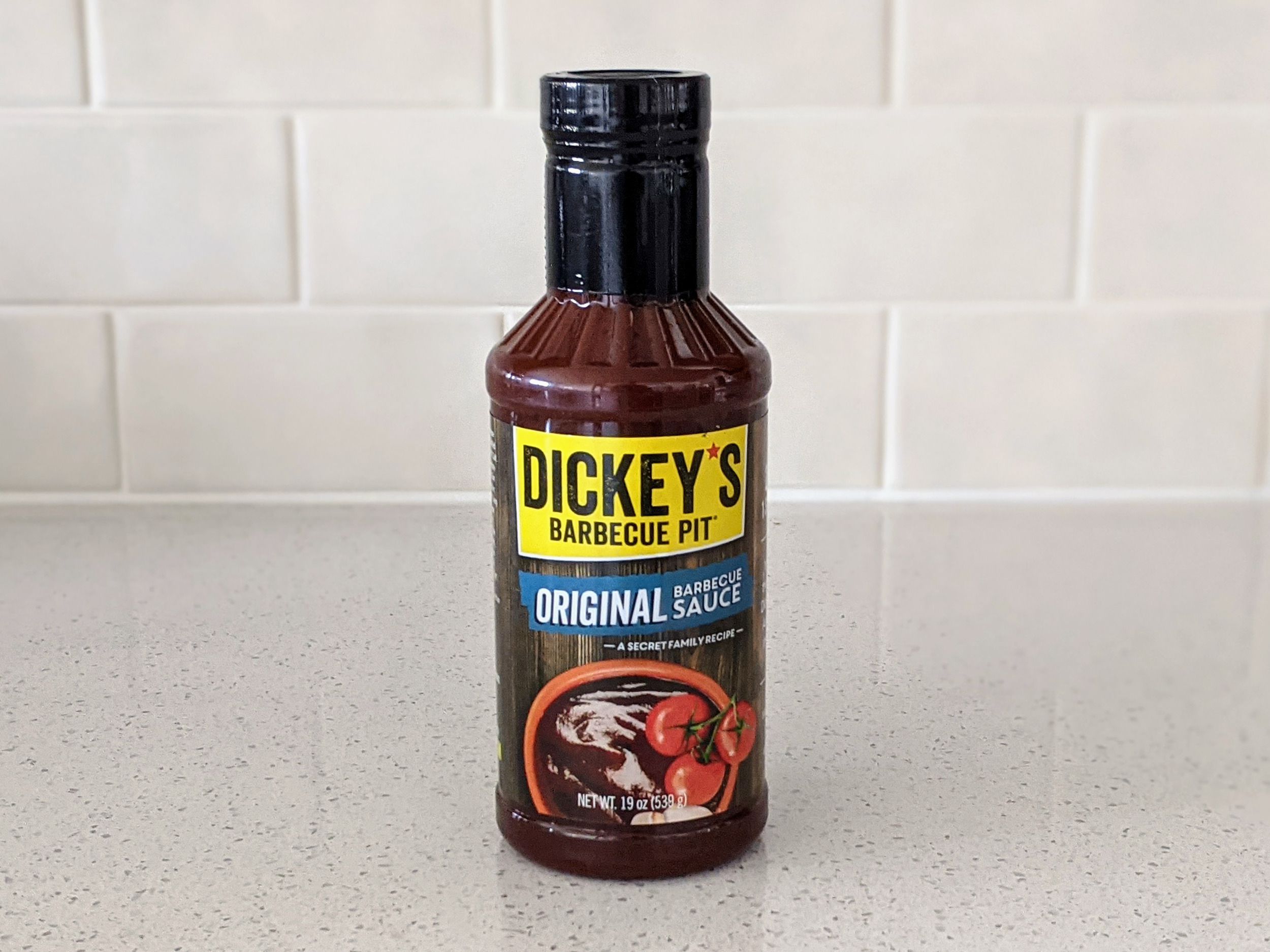 A Bottle of Dickey’s Barbecue Pit Original on a beige countertop, beige kitchen wall tile in the background