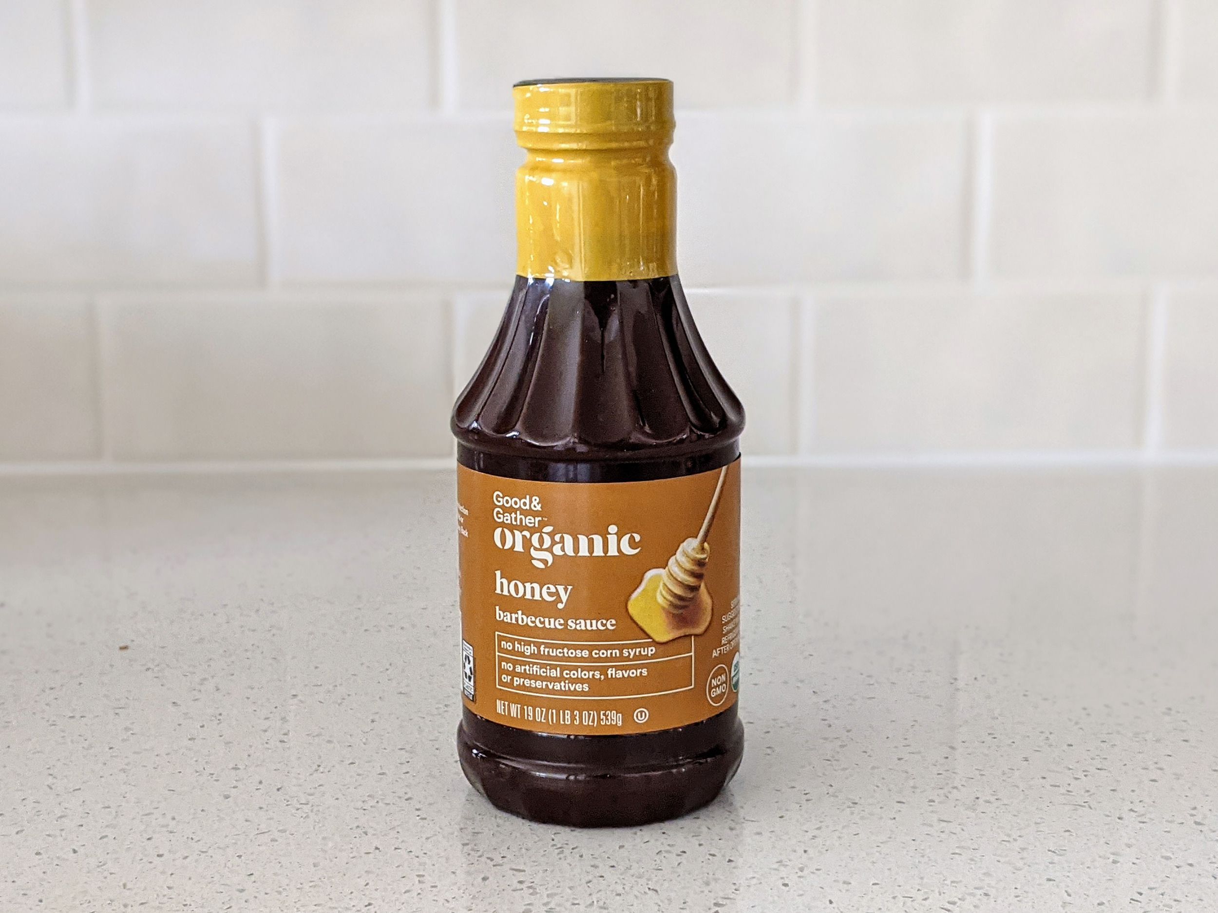 A Bottle of Good & Gather Organic Honey on a beige countertop, beige kitchen wall tile in the background