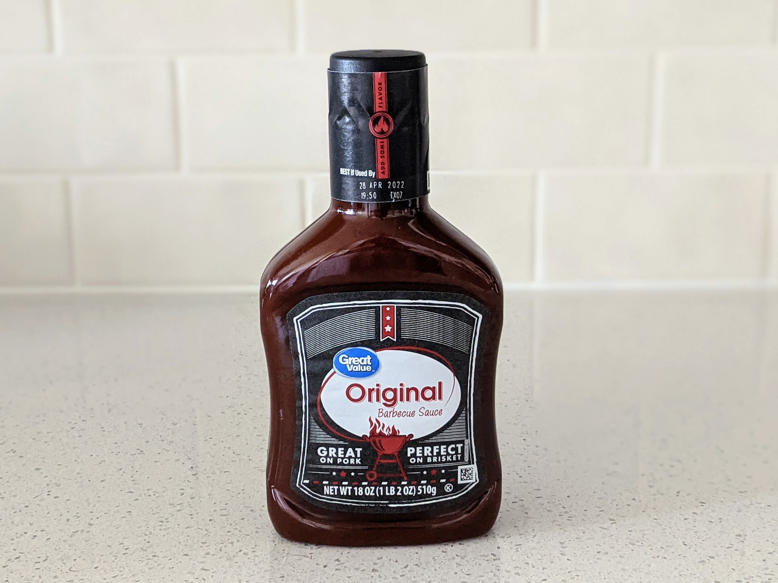 A Bottle of Great Value Original Barbecue Sauce on a beige countertop, beige kitchen wall tile in the background