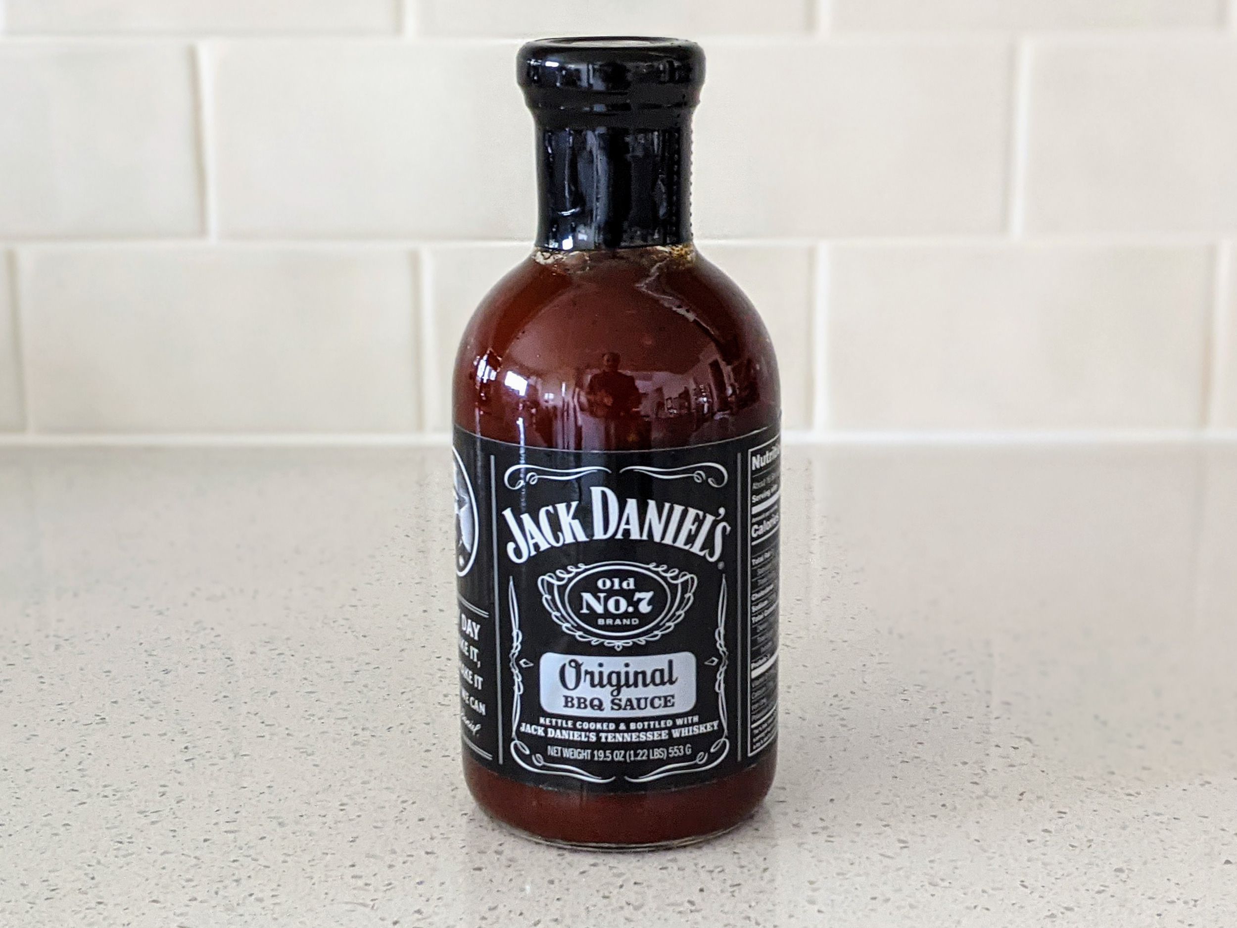 A Bottle of Jack Daniel’s Old No. 7 BBQ Sauce on a beige countertop, beige kitchen wall tile in the background