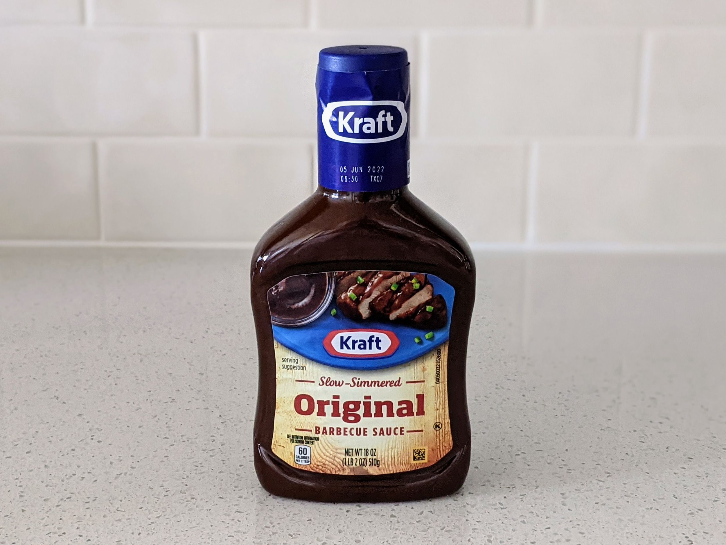 A Bottle of Kraft Slow-Simmered Original Barbecue Sauce on a beige countertop, beige kitchen wall tile in the background