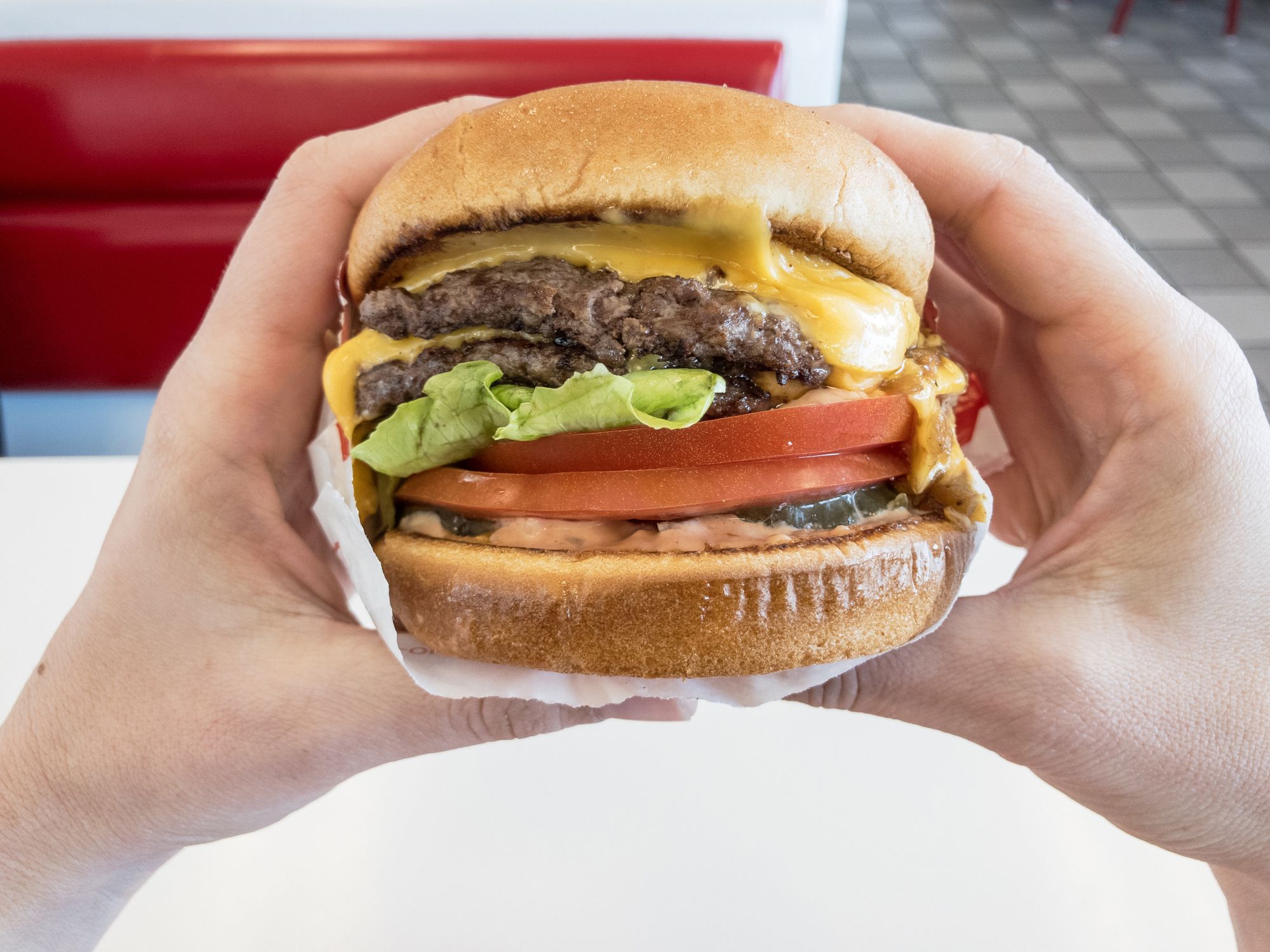 Hands holding a fast food double cheeseburger