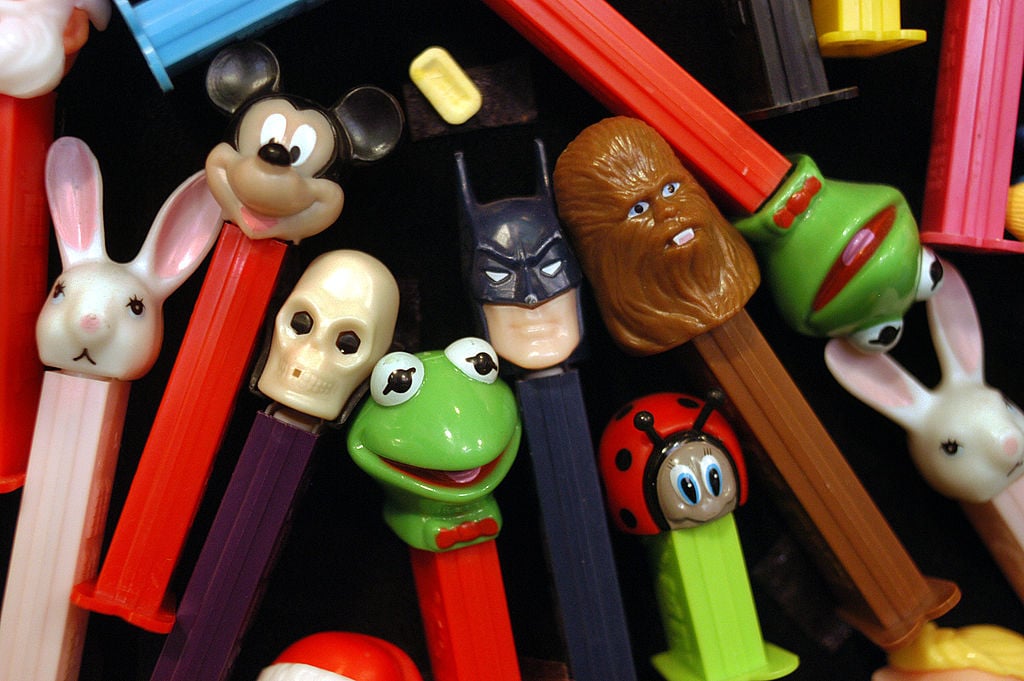 A colorful assortment of collectible toys, these PEZ dispensers feature characters like Mickey Mouse, Batman, Chewbacca, and more—all arranged closely together on a dark surface for fans of quirky collectibles.